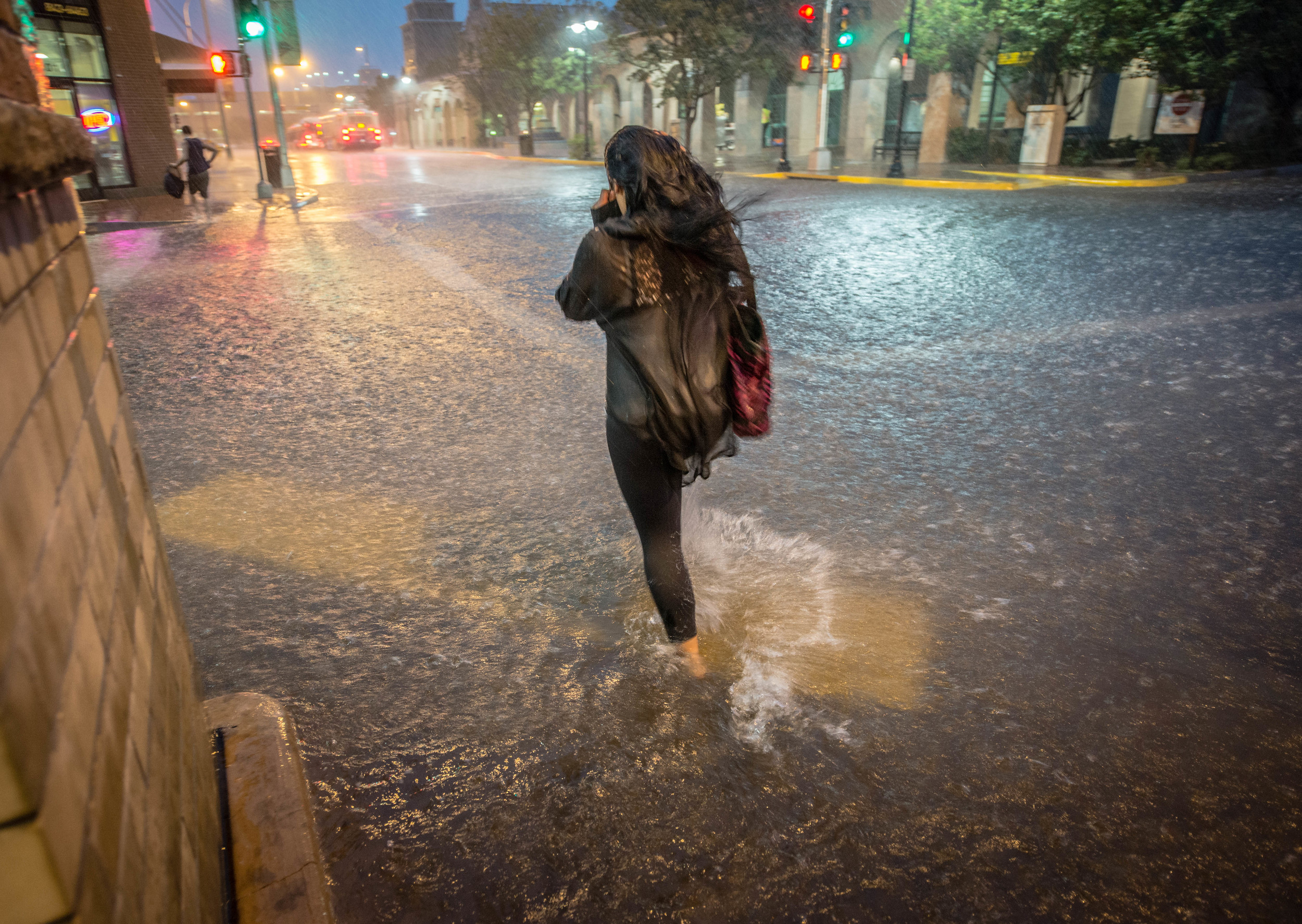 A woman walks across an intersection in downtown Albuquerque during a record storm.