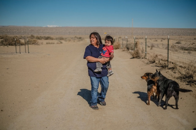 Cora Perry with her one year old Malichi Bryan walking in her front yard which sits next to the former site of a mill in Shiprock. (Roberto E. Rosales/Albuquerque Journal)