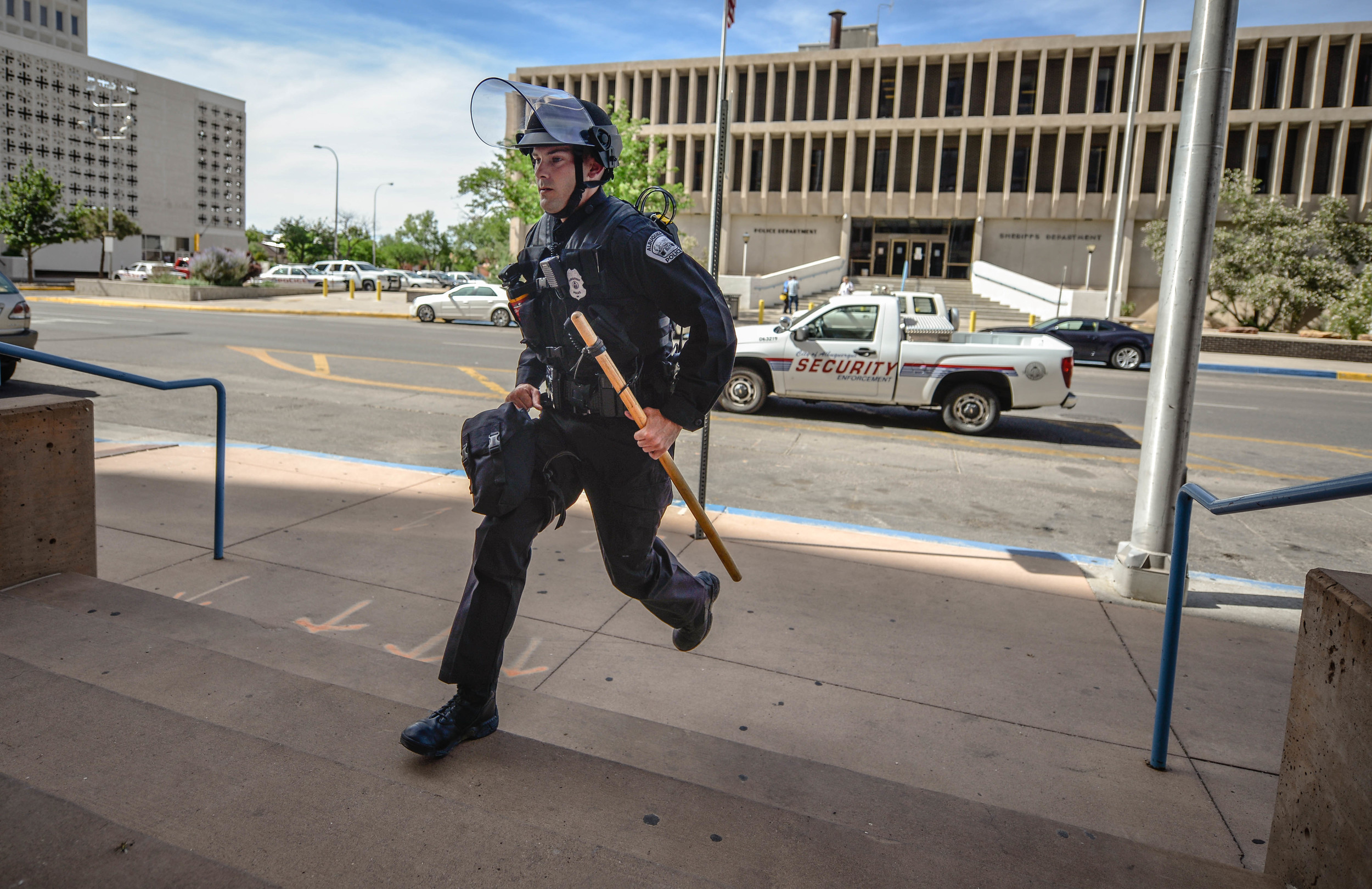 An Albuquerque Police officer runs up to the Mayor's office to arrest protesters.