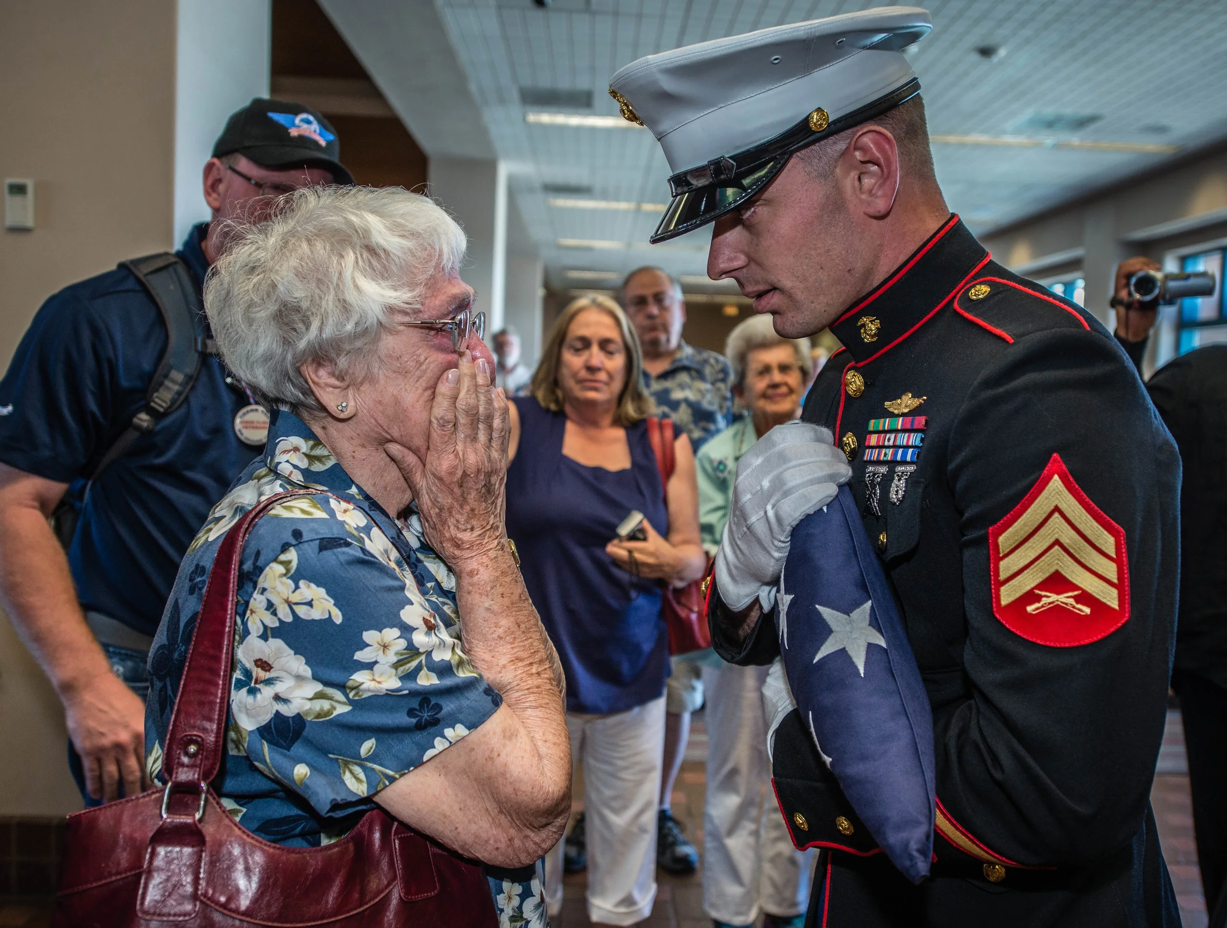 U.S. Marine Corps Sgt. Nicholas McCreary presents an American flag to Charlotte Clark of Albuquerque on Friday at the conclusion of an Honor Flight, during which 22 New Mexico World War II veterans returned from an all-expense-paid trip to visit the National World War II Memorial in Washington, D.C. Clark’s husband, Arthur Clark, had signed up for the Honor Flight but passed away in April. She was also presented a framed photo of her husband in his World War II Marine uniform. (Roberto E. Rosales/Albuquerque Journal)
