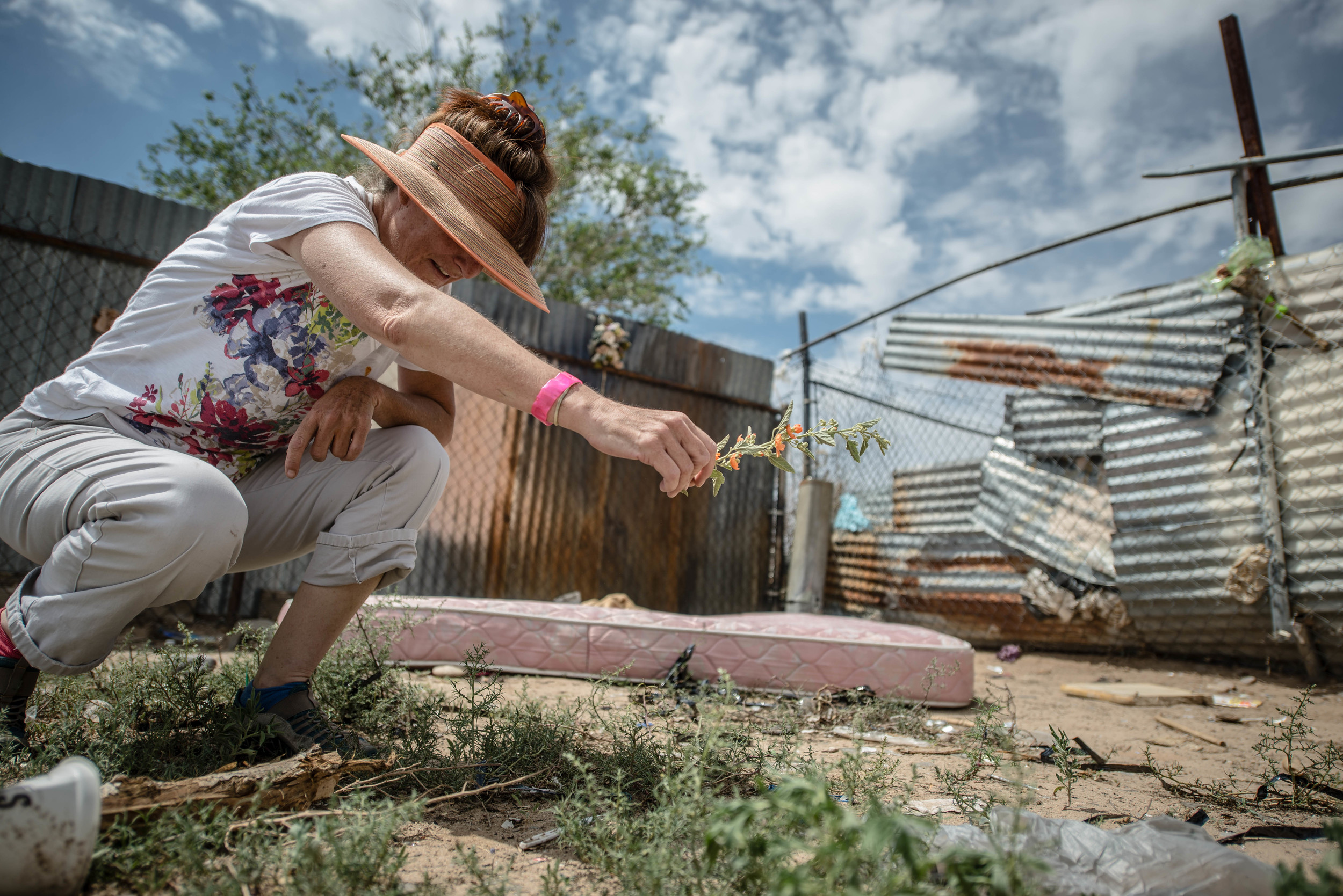 A woman picks wildflowers in the empty lot where two homeless men were attacked in their sleep and beaten to death – so badly they could not be recognized. (Roberto E. Rosales/Albuquerque Journal)