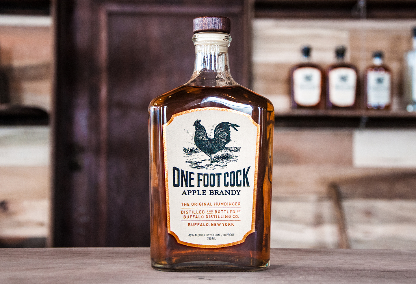 One Foot Cock Apple Brandy: Aged A true gentleman's brandy, One Foot Cock Apple Brandy is the " Original Humdinger " for sure. We ferment the finest apples in the world fresh from local Smith's Orchard and double distill in our custom pot still. Aged in oak barrels for exceptional smoothness allowing for a robust apple & vanilla aroma at first glance with a delectable smoky finish. Whether you find yourself stranded on the side of a frozen alp or relclined by a crackling fire, One Foot Cock Apple Brandy is your perfect companion. For recipes click here.
