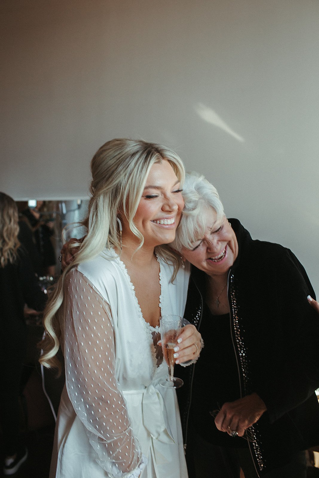  A bride laughing and hugging her grandmother on her wedding day. 