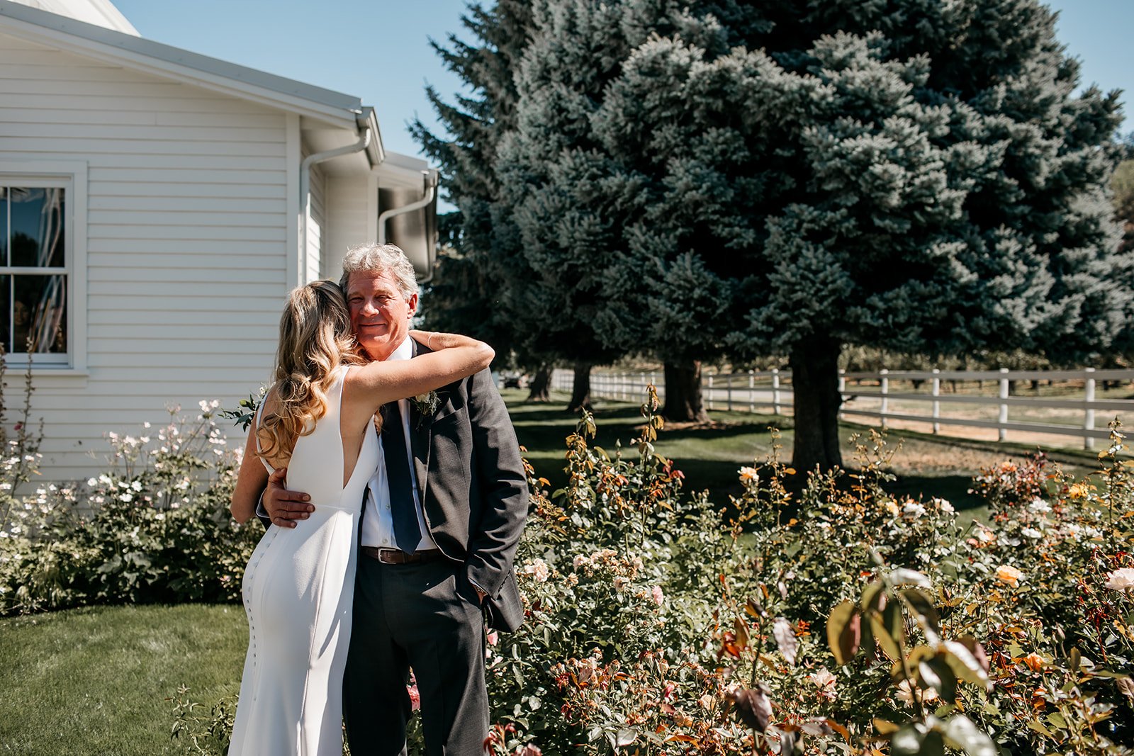  The bride wearing Alyssa Kristin Maven wedding dress hugging her father outside in the garden on her wedding day. 