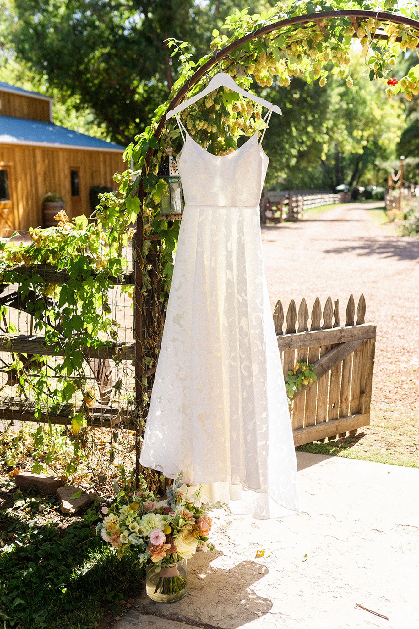  Annie wedding dress by Truvelle bridal handing on an arbor in a garden in Colorado in the springtime. 