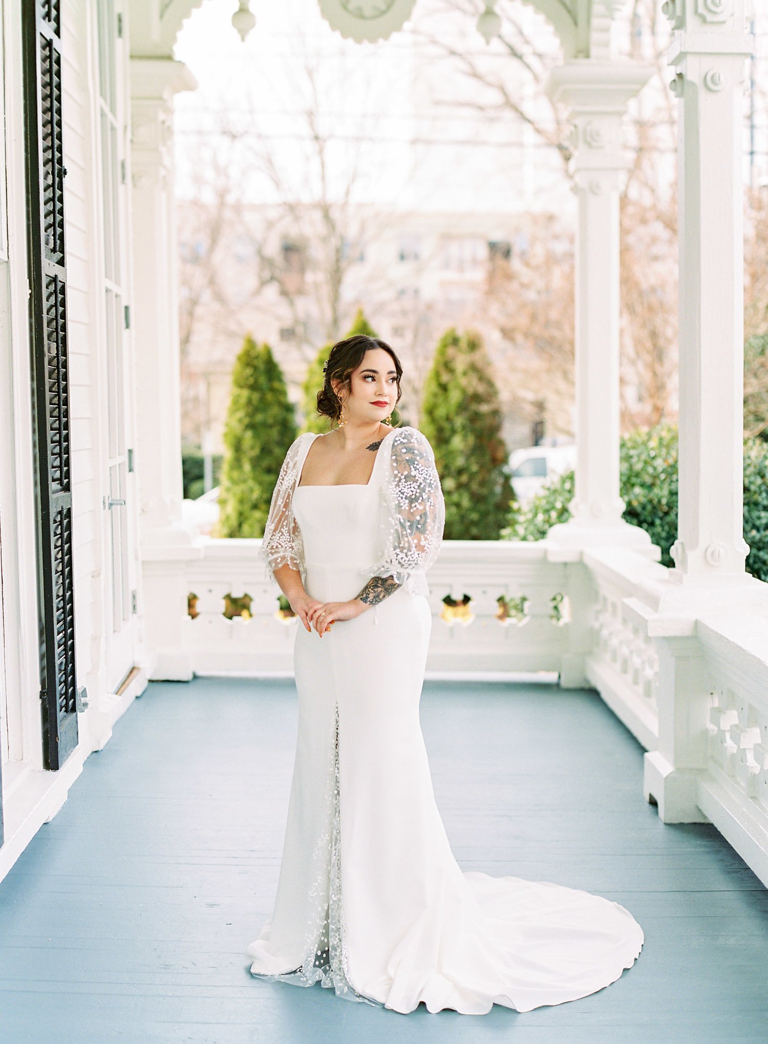 a bride wearing florence by laudae wedding dress standing on a victorian porch for an outdoor spring wedding in north carolina 