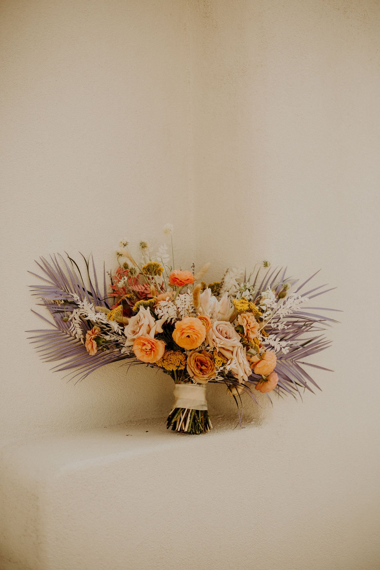  a boho desert bridal bouquet with orange, peach, purple, yellow, and green flowers 