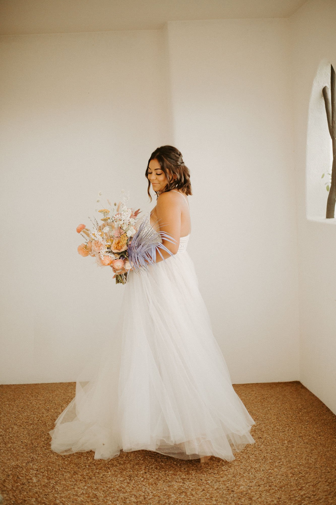  a fun modern bride wearing the thistle wedding dress by willowby by watters bridal and holding a colorful and boho bridal bouquet with purple, peach, and blush flowers 