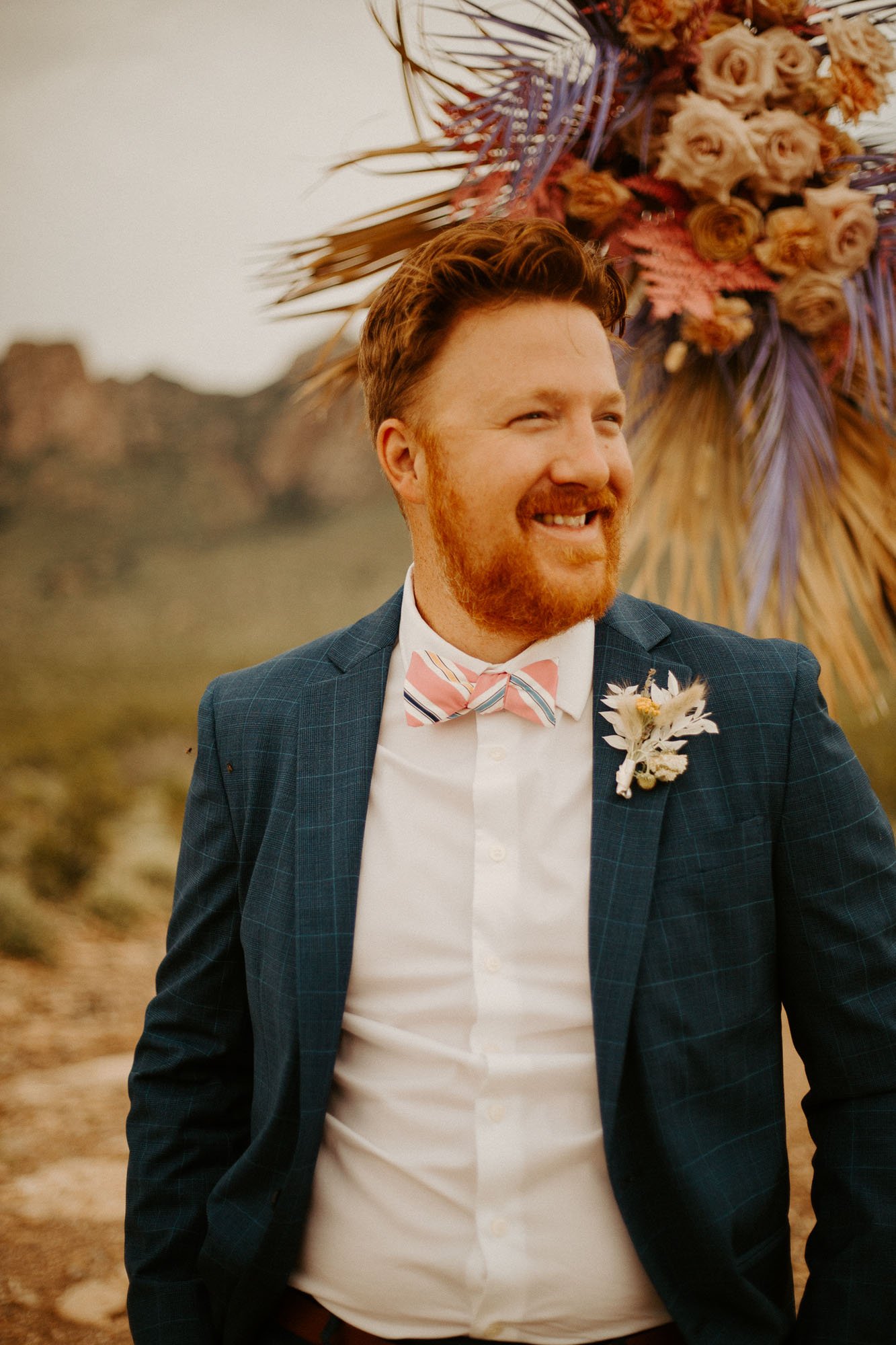  a groom with red hair and a beard wearing a blue plaid suit and a bow tie for a new mexico boho desert elopement 