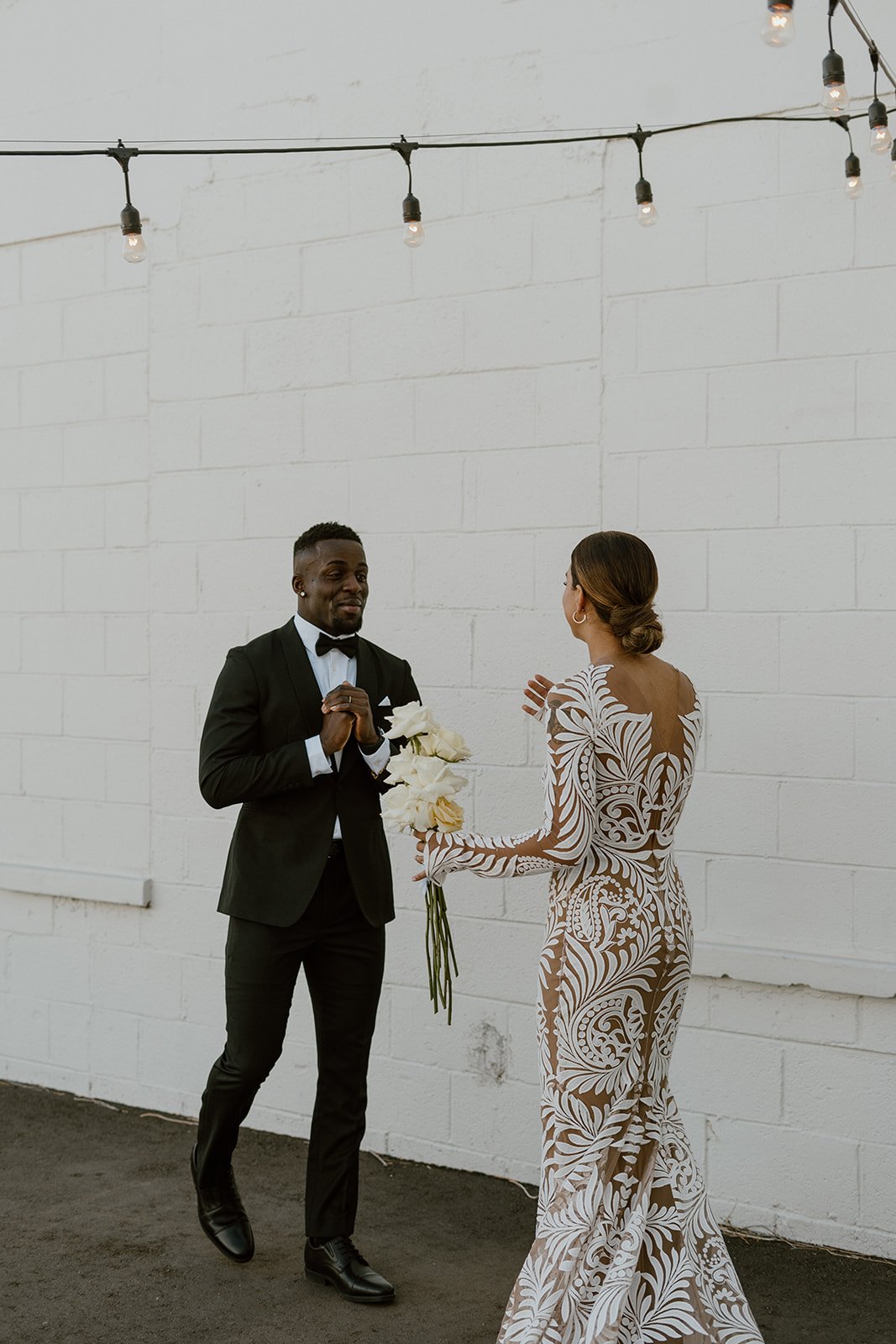  a bride and groom sharing an emotional first look before their wedding ceremony. the bride is wearing rue de seine reno wedding dress, which is a long sleeve fitted wedding gown with bold lace and a nude illusion mesh. 