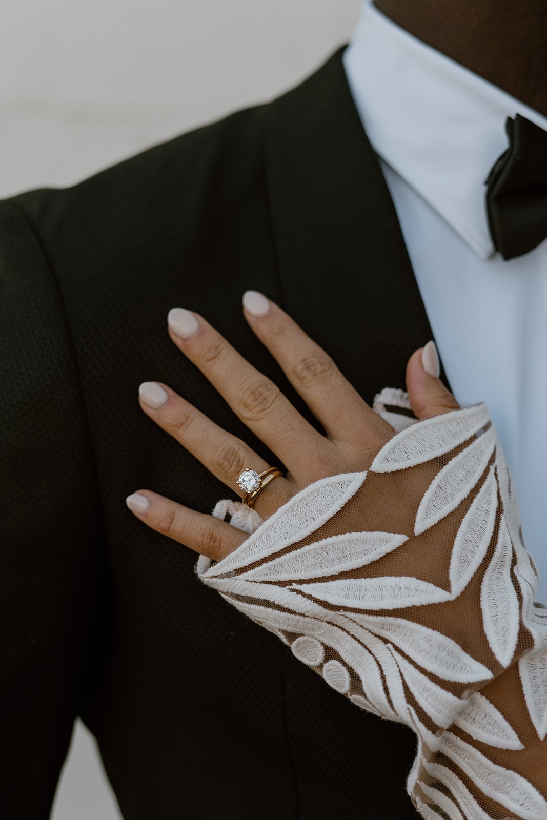  an up close of a bride’s solitaire diamond wedding ring with a thin gold band. the bride is wearing the rue de seine reno wedding dress. 