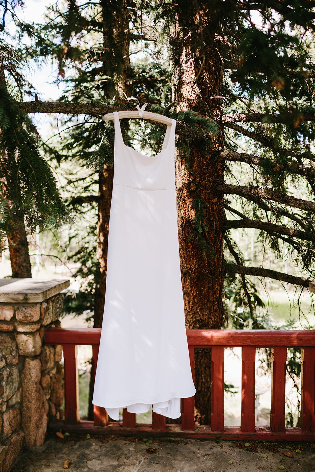  Alyssa Kristin Sydney wedding dress hanging from a lovely pine tree on the gorgeous balcony of a mountain lodge 