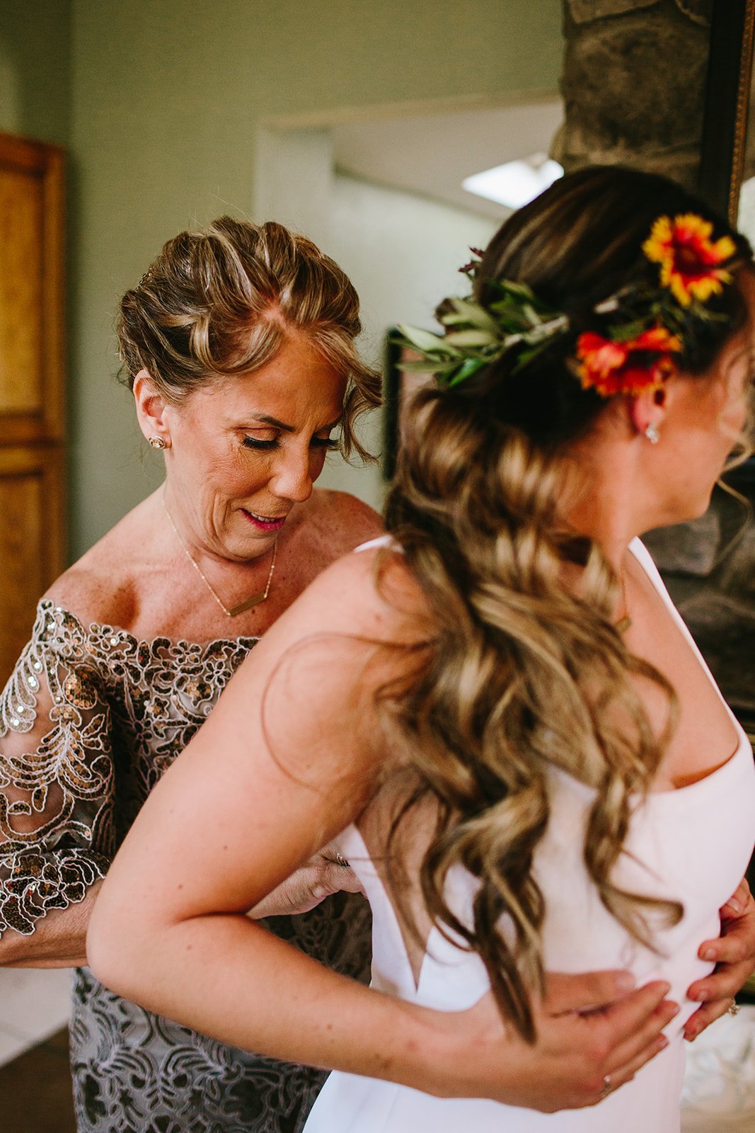  a loved one zipping a bride into their Alyssa Kristin Sydney wedding dress for a lovely outdoor Colorado wedding 