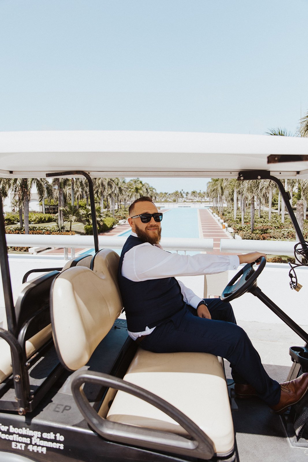  A groom driving through a resort in Mexico in a golf cart on the way to the wedding ceremony 