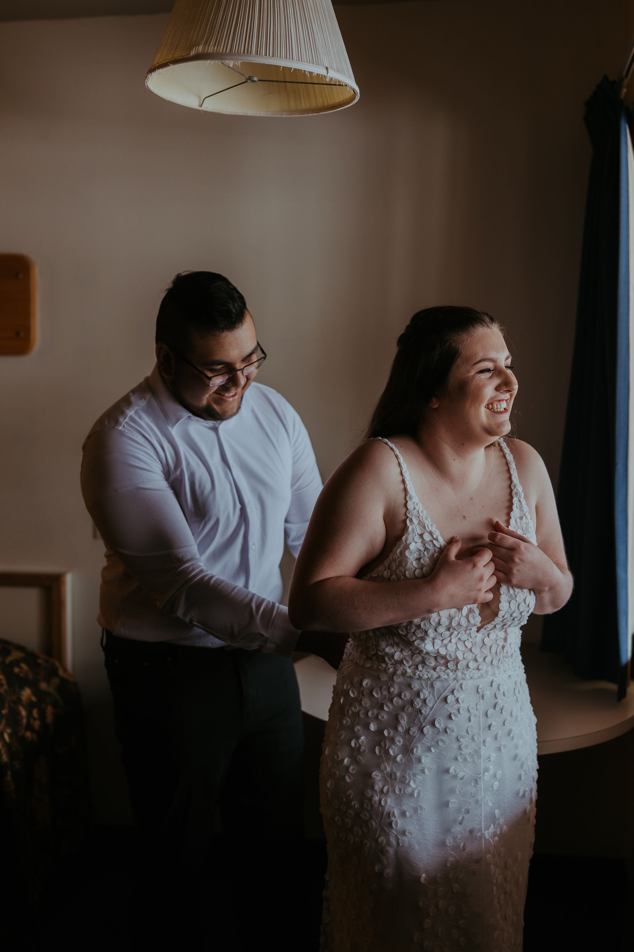  A bride and groom getting ready together for their snowy mountain elopement in Boise, Idaho. The bride is wearing Made With Love ‘Louie’ wedding dress. 