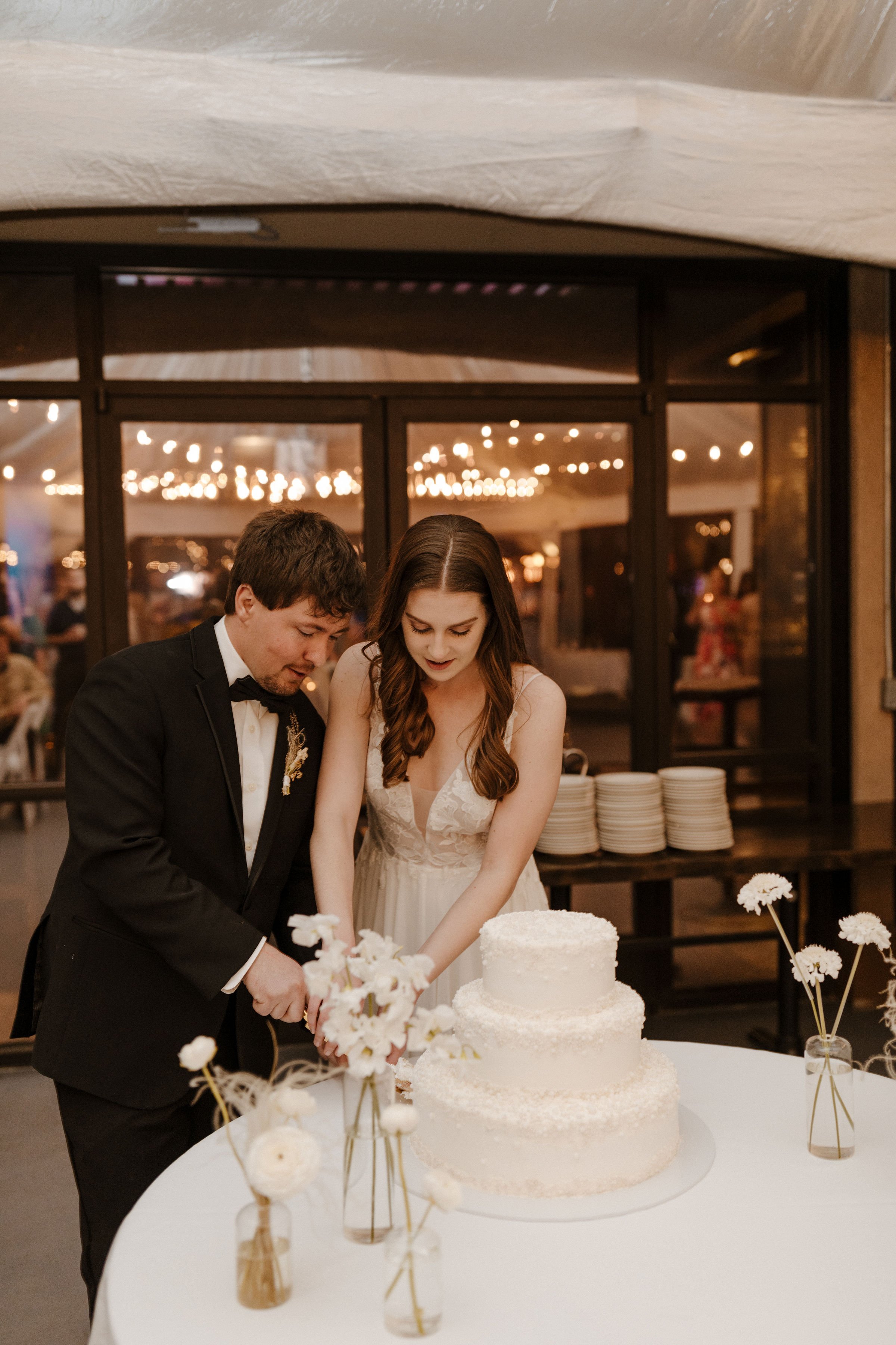 cute wedding couple cutting the cake at thier ceremony featuring cambria by jenny by jenny yoo