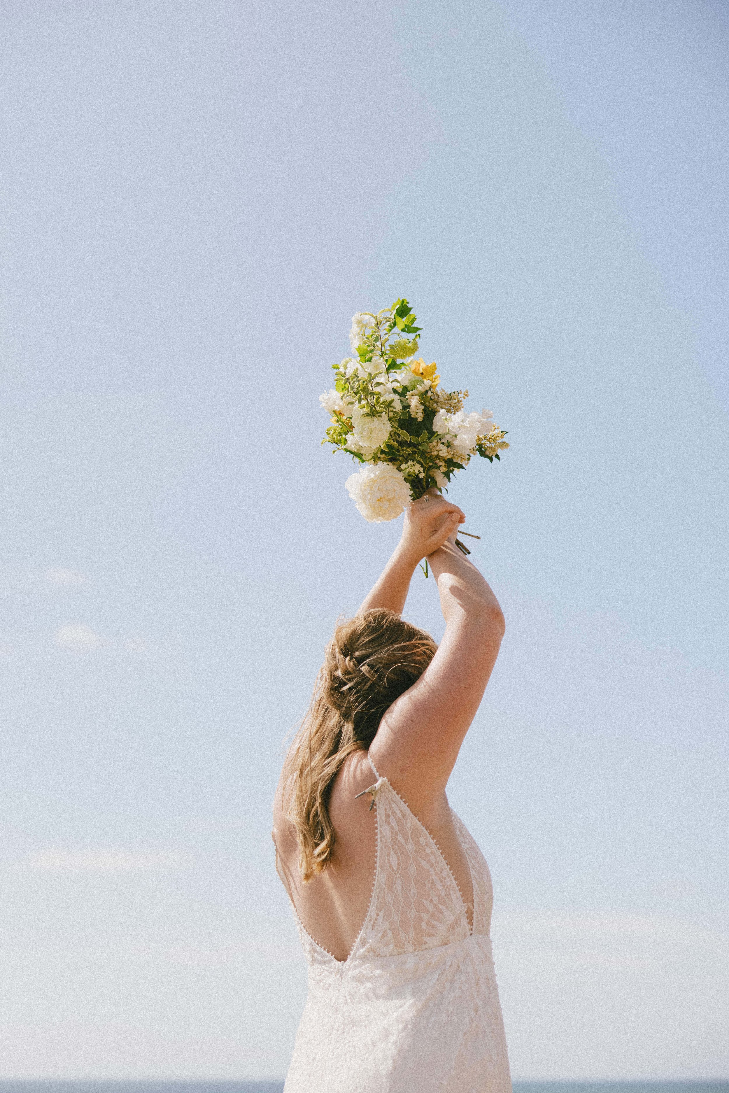 a coastal beach bridal portrait with a rish wedding dress and greenery bouquet