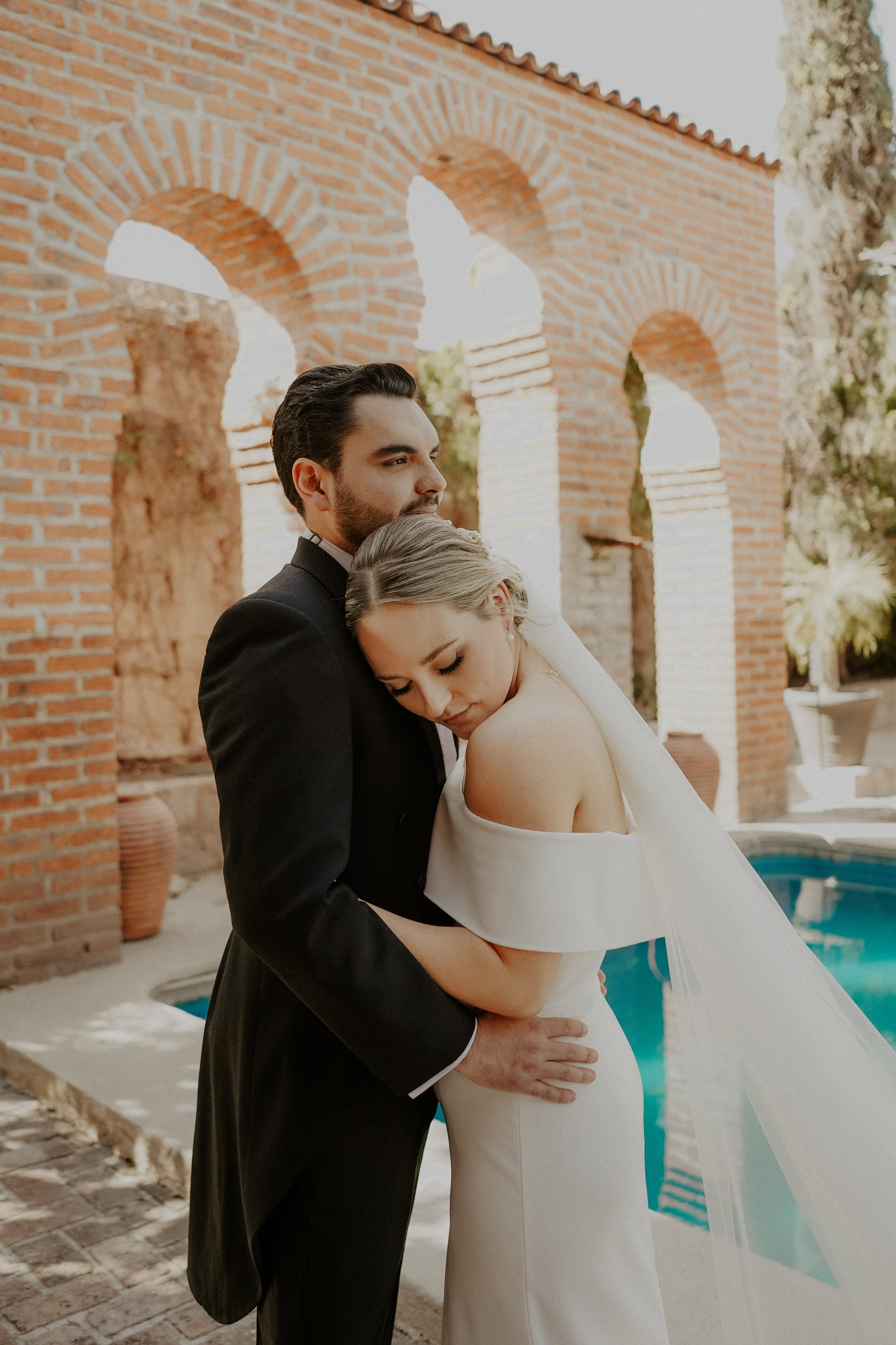 the couple has a warm embrace after the first look featuring the crepe off the shoulder vagabond gown.