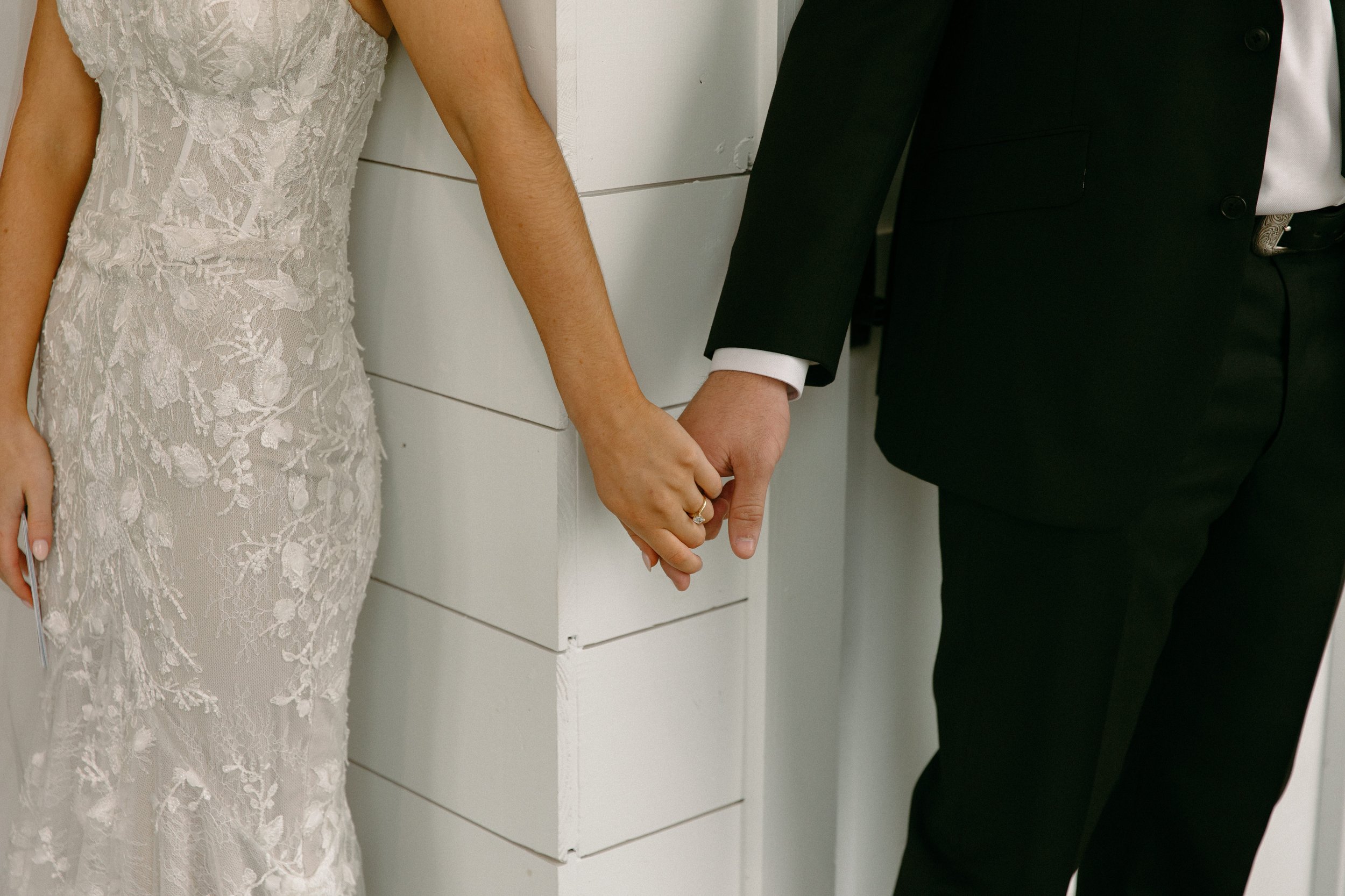 a first look with holding hands between the bride and groom at the gardenia venue in texas.