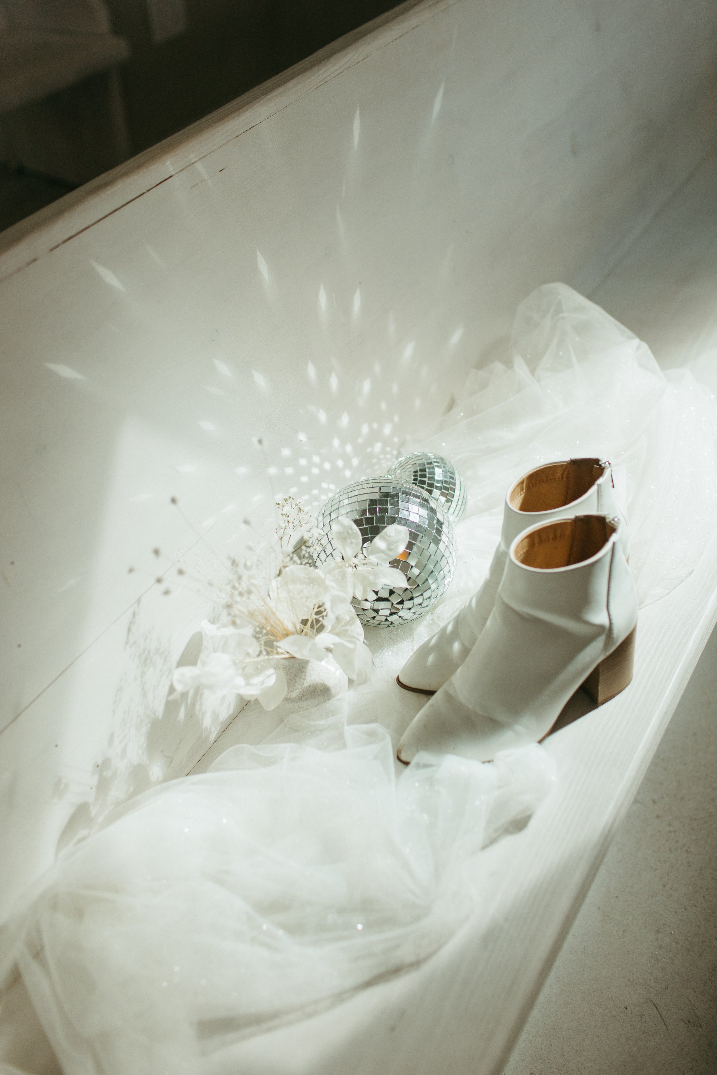 cool disco ball wedding details with white cowboy boots in a modern all white church