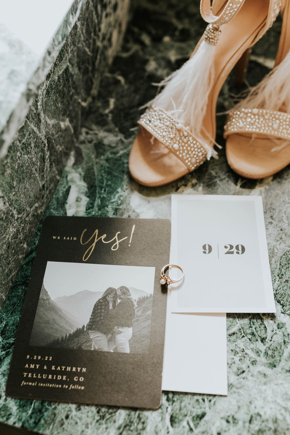  a styled flatlay of wedding invitations for brides kathryn and amy featuring their invitation, save the date, wedding shoes, and wedding rings 