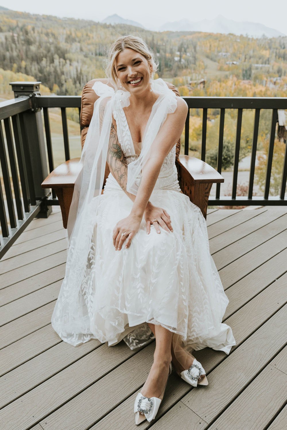  a bride wearing rish ‘selene’ wedding dress and made with love ‘elsie bows’ relaxing in a cabin balcony in telluride, colorado before her wedding 