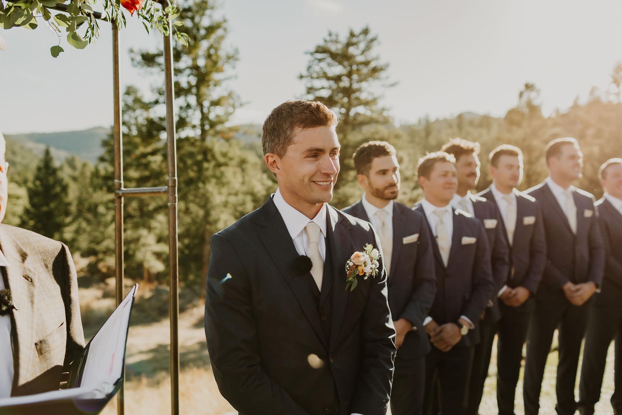  A groom smiling as he gets a first look at the bride walking down the aisle towards the alter. 