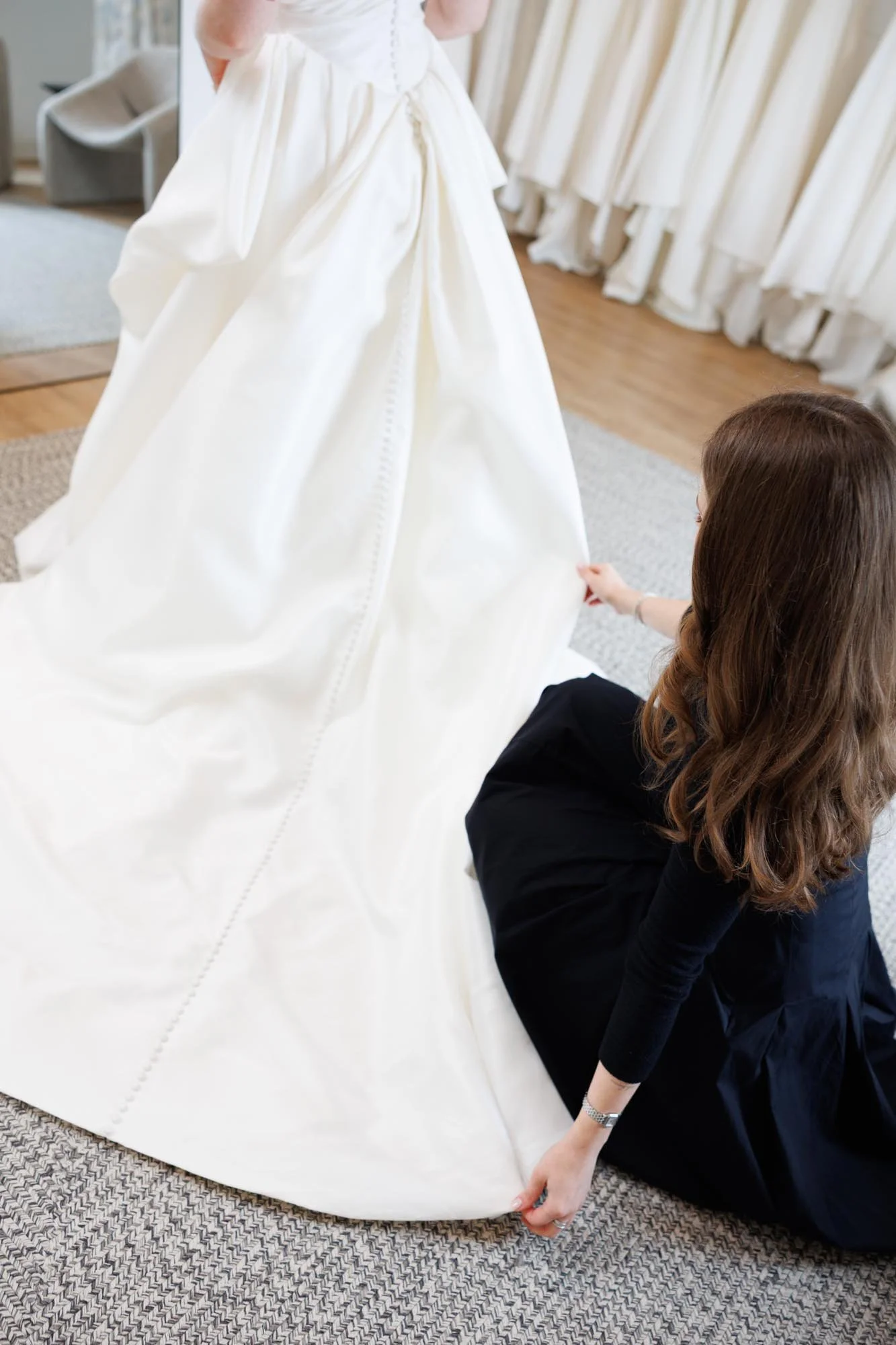 A stylist helping a bride try on a wedding dress at a&bé x anna bé Dallas bridal shop