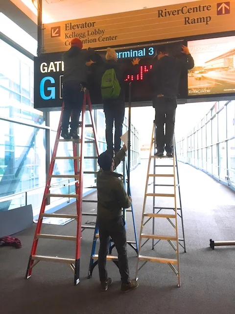 Local 490 Art Dept hangs new signage to transform a St.Paul skyway into an airport.