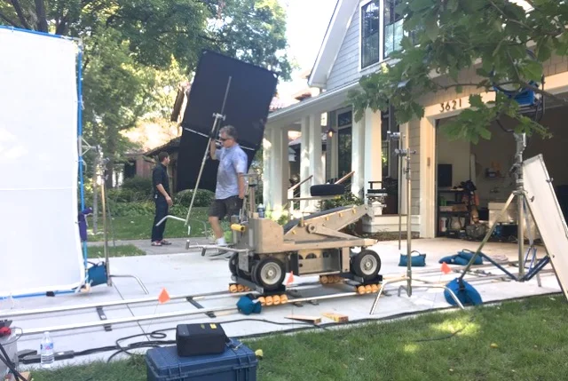 Grip Dan Miller moves a 4x4 floppy past the dolly track. Photo provided by Ariss Locations.