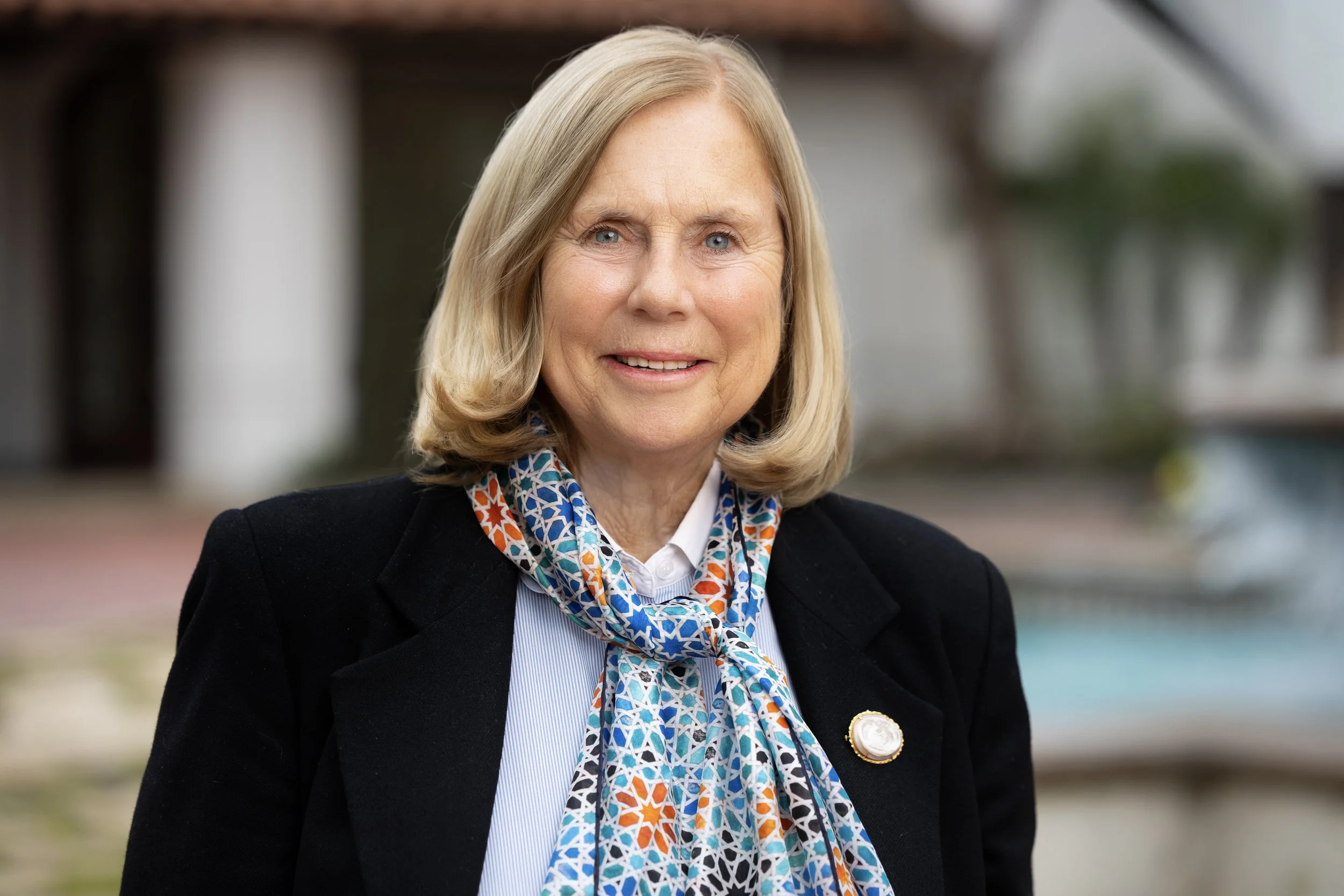 Portrait of City Counselor Margaret Finlay in a black blazer, blue shirt, and colorful scarf
