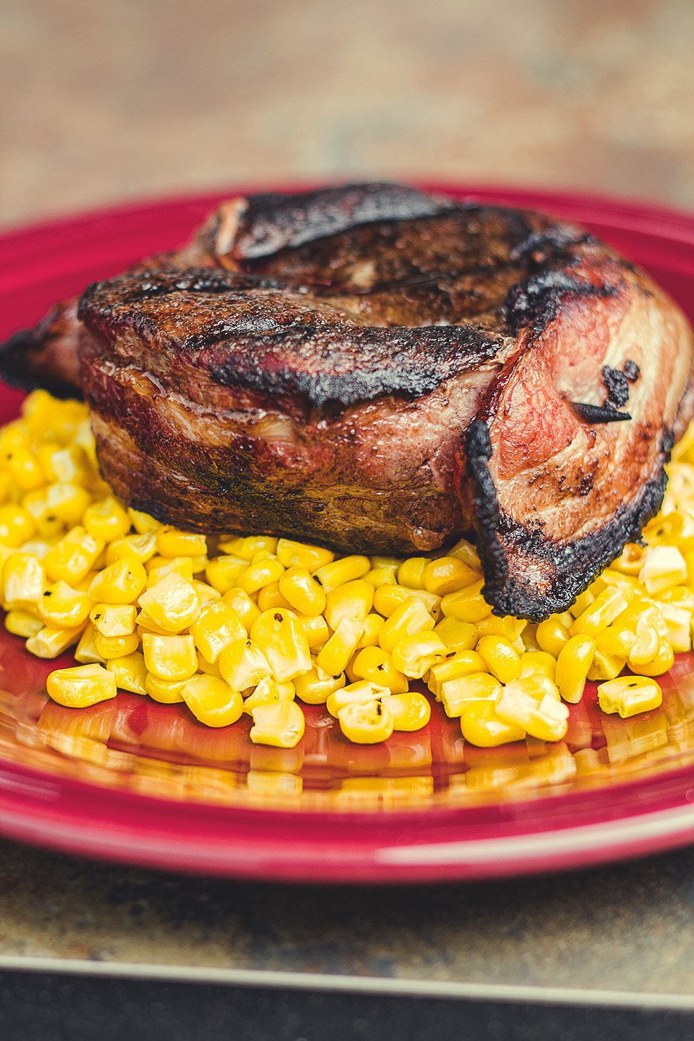 A prime example of my first failed attempt of shooting food. A huge steak on top of a pile of weirdly colored corn on a red plate. Yikes!