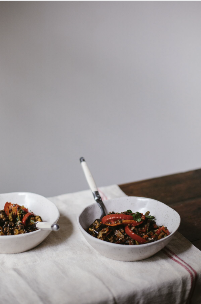 Two bowls of vegetable stir-fry on a cloth-covered table