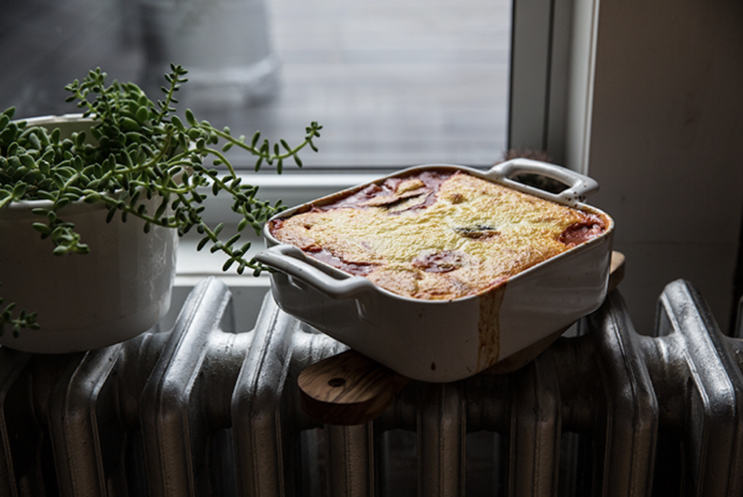 Baked casserole dish next to a potted plant on a radiator by a window.