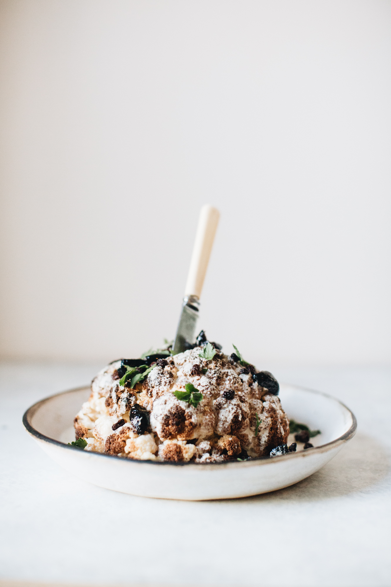 Whole roasted cauliflower with herbs and spices on a plate