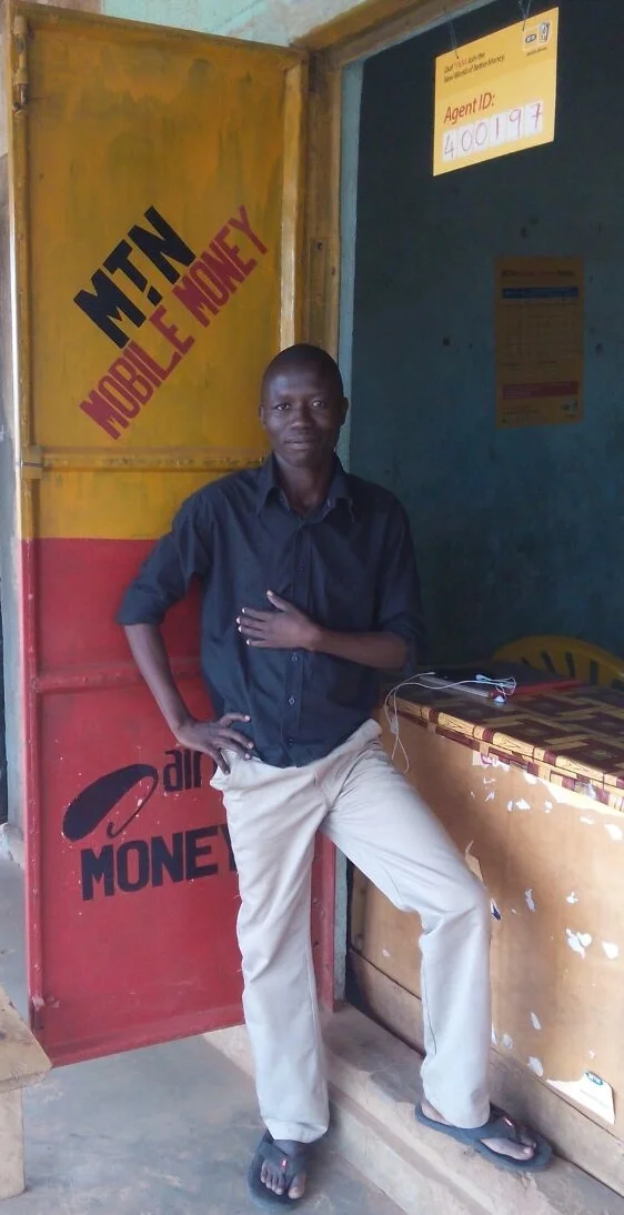 George, right, assisting a customer at one of his mobile money stores.