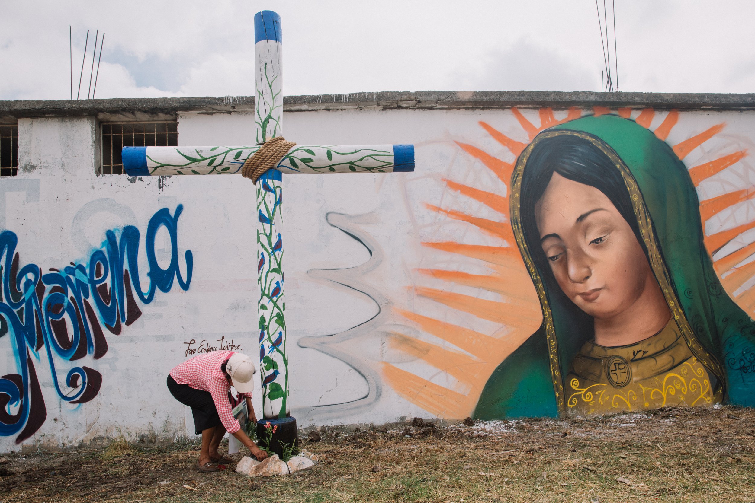  Maria Gloria Cabrera places flowers at the foot of a cross marking the site of a mass grave where unidentified migrant bodies are buried Nov. 29, 2016, at Panten Municipal Domingo de Ramos en Juchitn, Oaxaca. The location is in the process of beco