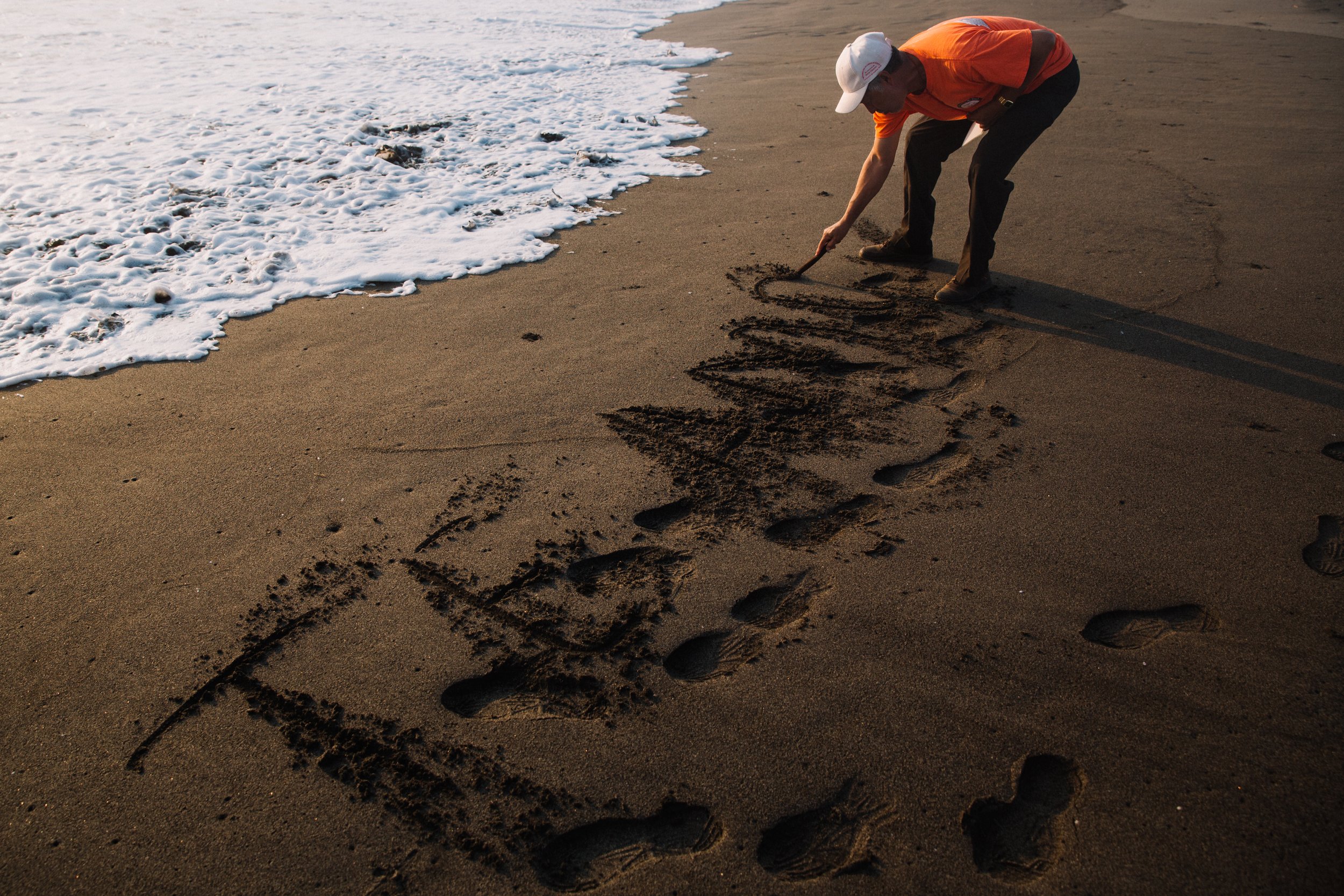  Hector Felipe Rodriguez, a father from Honduras, writes a heartfelt message in the sand at Barra de San Jose, Villa Mazatan, Chiapas, Mexico, a new route taken by many migrants due to the dangers of traditional routes under the Frontera Sur border p