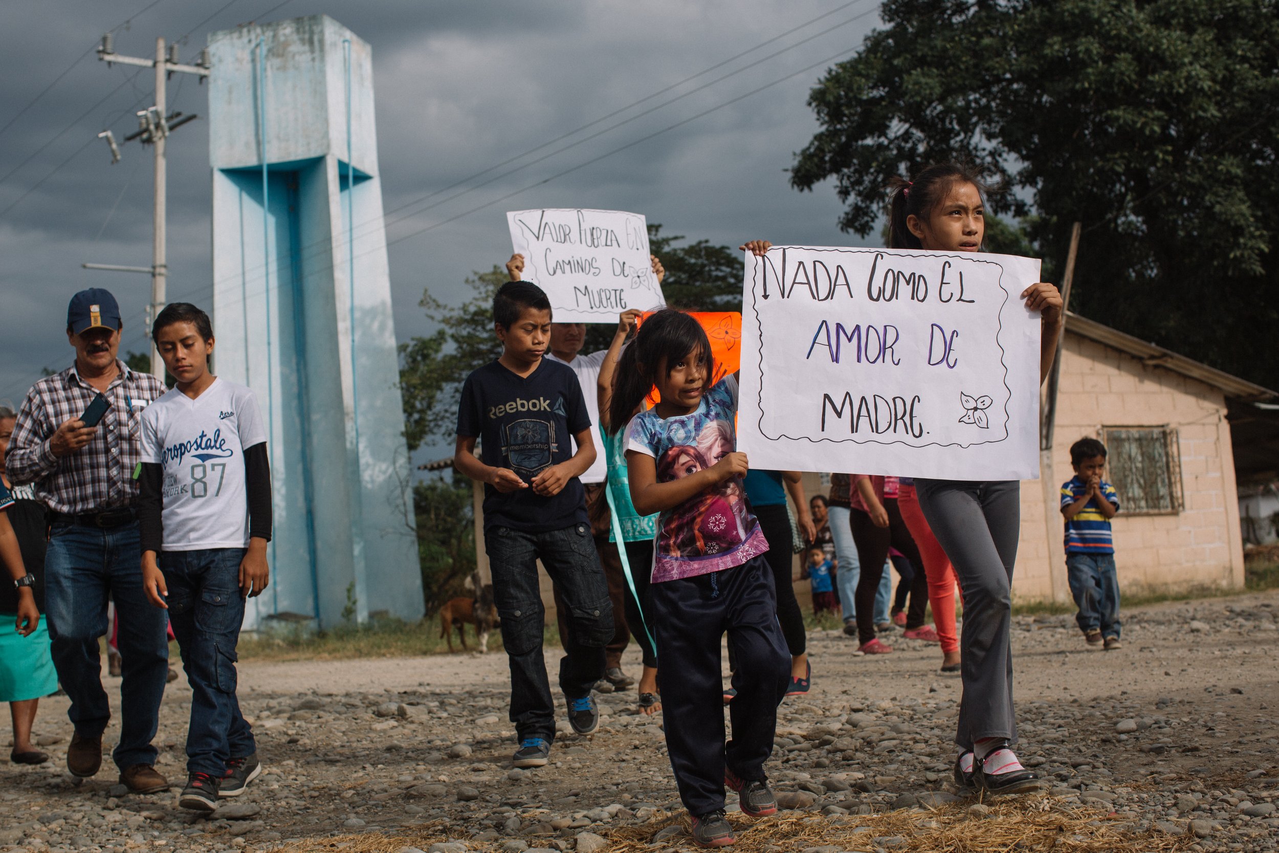  In a heartwarming scene, children from the community of Nueva Linda in Chiapas, Mexico, run out to greet the caravan of mothers with signs of encouragement. Nueva Linda is a common stop for migrants on their way north, and the community often hires 