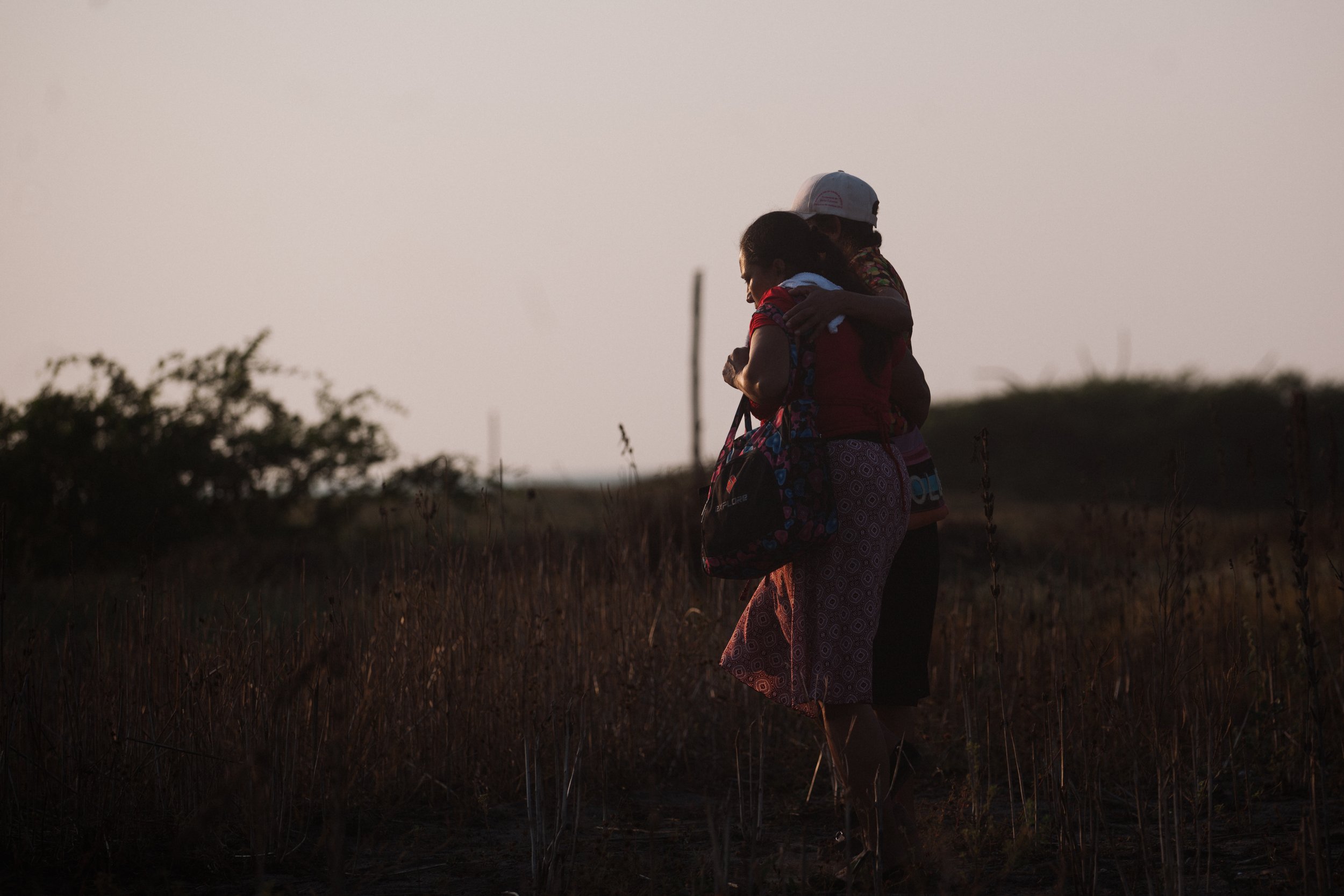  Two mothers find comfort in each other's embrace as they walk back to the caravan after a long and exhausting day of traveling. 