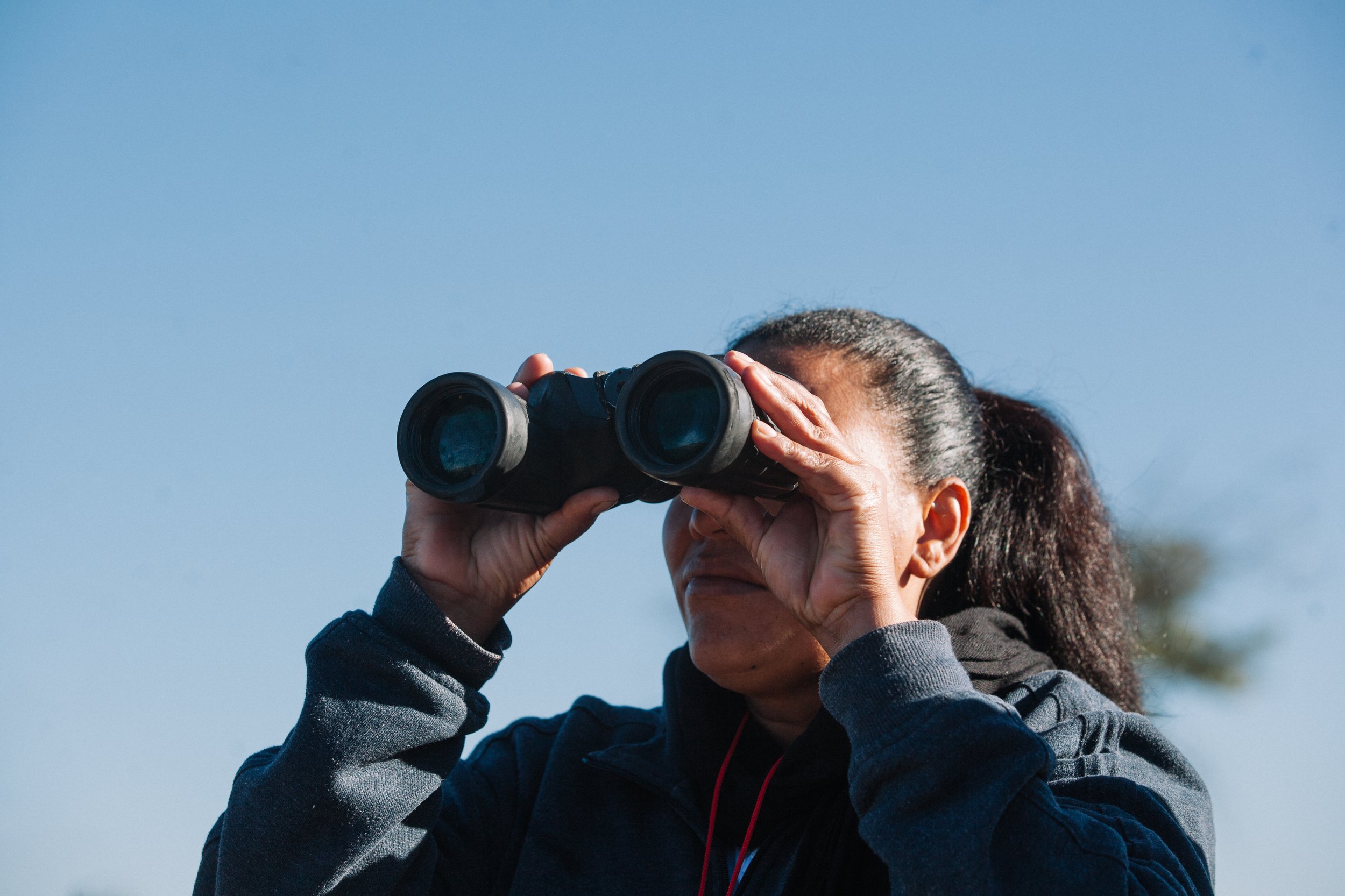  Nohemy Yamileth Alvarez gazes through binoculars, witnessing a group of migrants crossing into Arizona with a mix of emotions - hope and sadness. She wonders if her own missing son had taken a similar path, adding to her empathy for those striving t