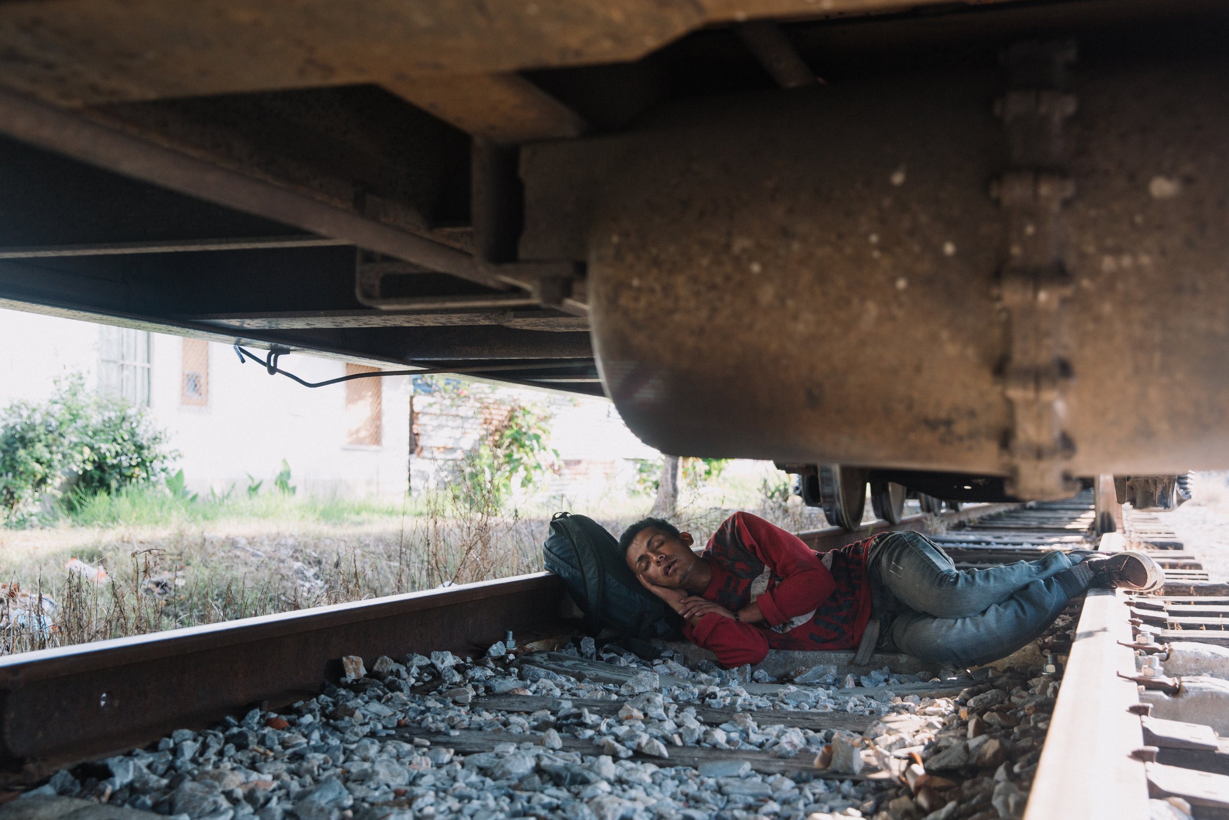  As a freight train rumbles through a neighborhood of Coatzacoalcos, Veracruz, a migrant takes advantage of a moment of stillness to catch some sleep. For many migrants, the journey through Mexico involves hopping on and off moving trains, often in d