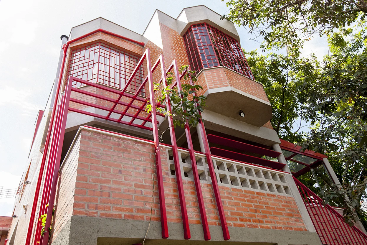 Tijolos maciços, cobogós de concreto e elementos metálicos vermelhos foram utilizados para garantir uniformidade do volume da nova varanda com o da casa.