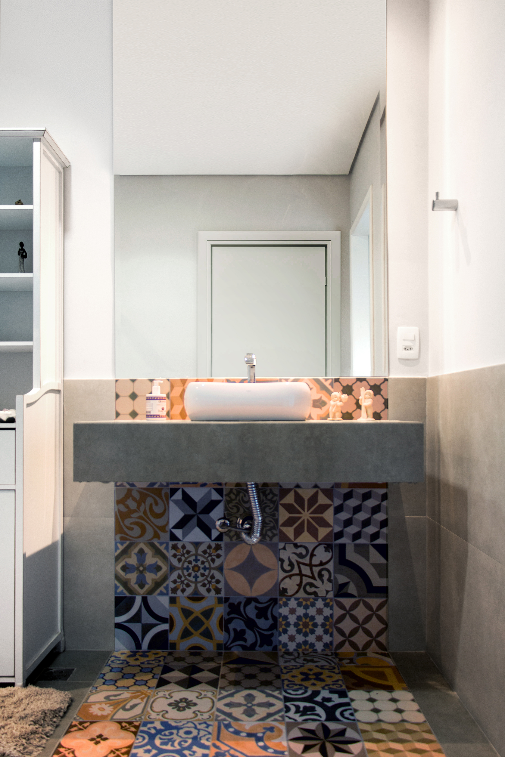 Banheiro com faixa de ladrilhos no piso e na parede, bancada revestida com porcelanato.