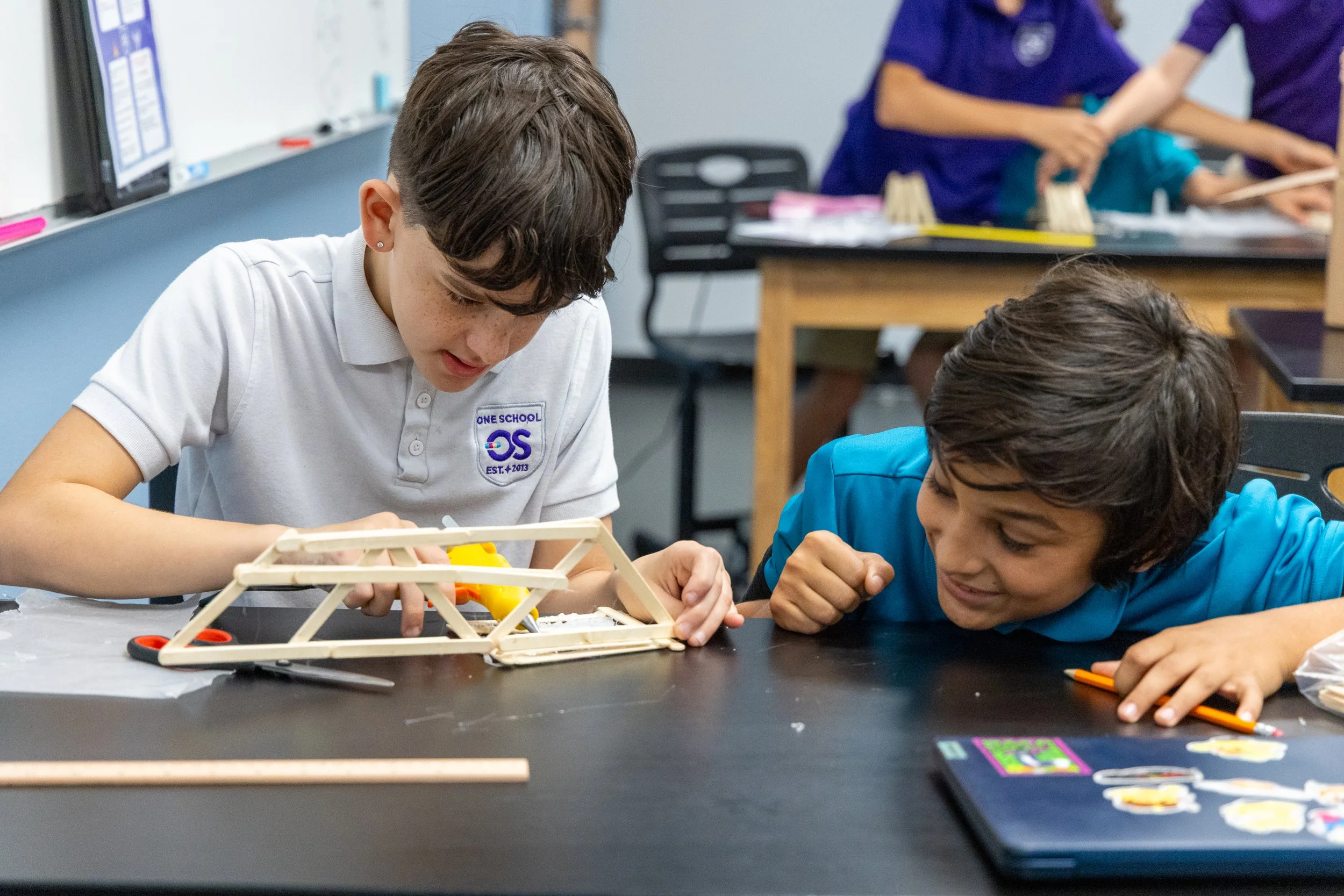Two students working on a science project with a wooden model of an aircraft in a classroom.