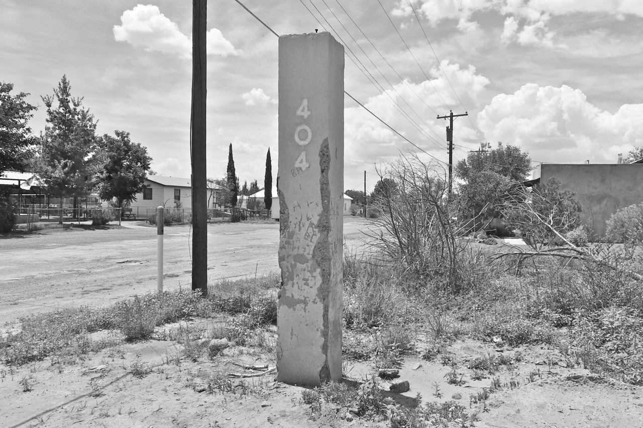 15 August 2014: We have a street address! This existing column, made from flesh-colored concrete, is covered with various carvings and graffiti. There used to be another one, on the other side, but it was gone before we got here. Last week, a woman drove by looking for the other one. When they were little, she said, her husband carved their names in a heart there.