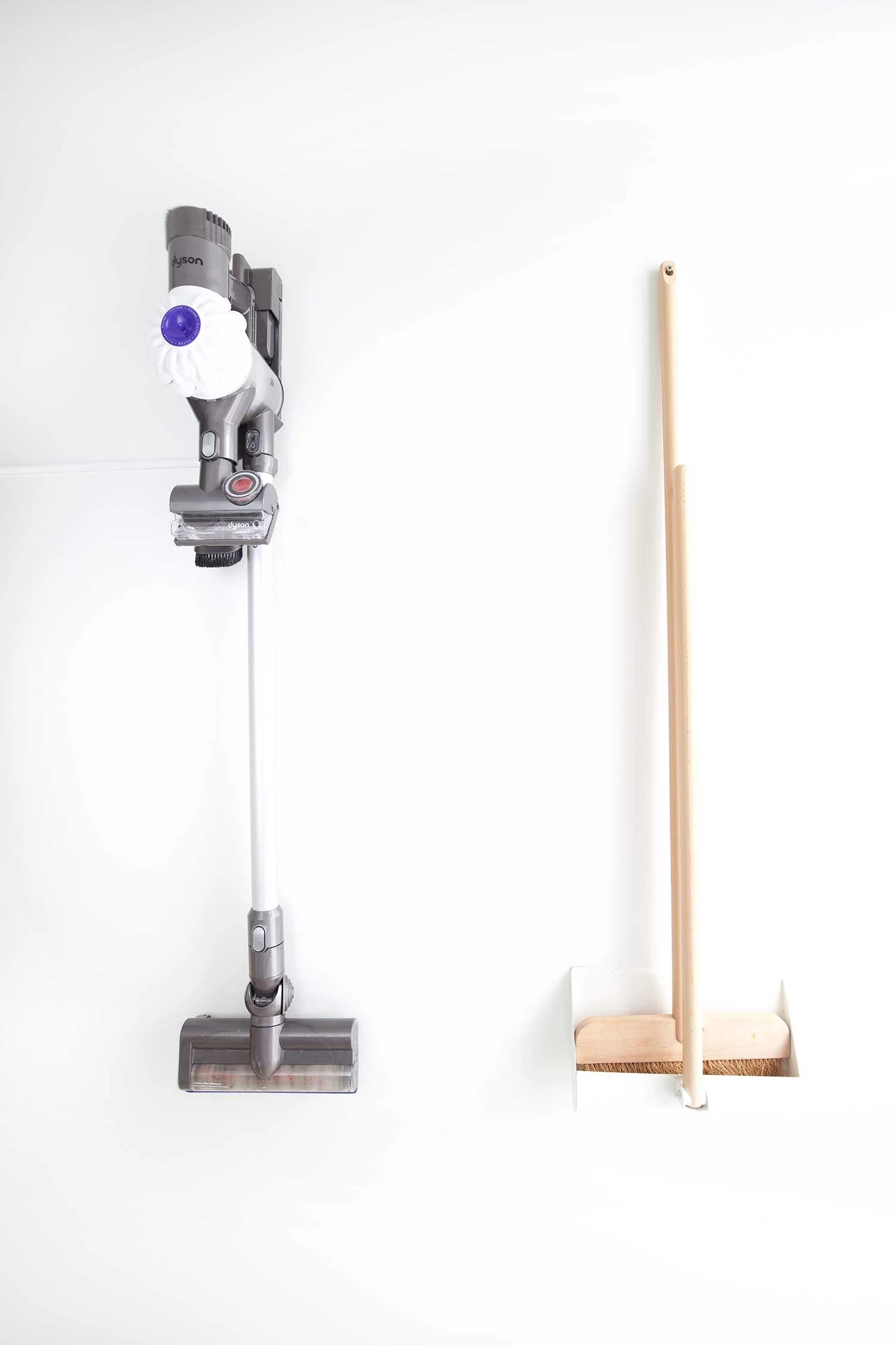 hanging vacuum and broom in organized pantry