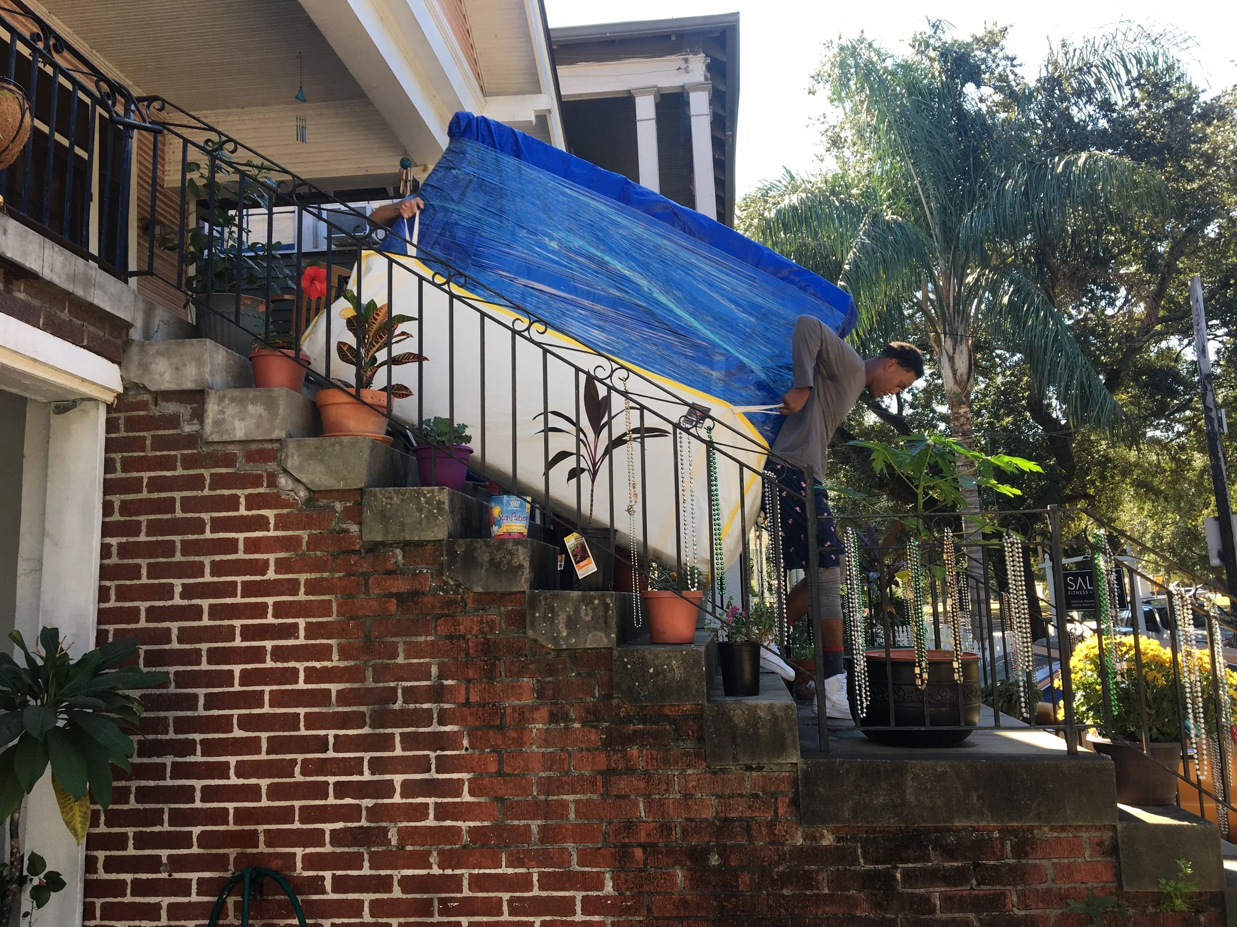 Mattress protected with a reusable tarp is easily transported using a mattress sling.