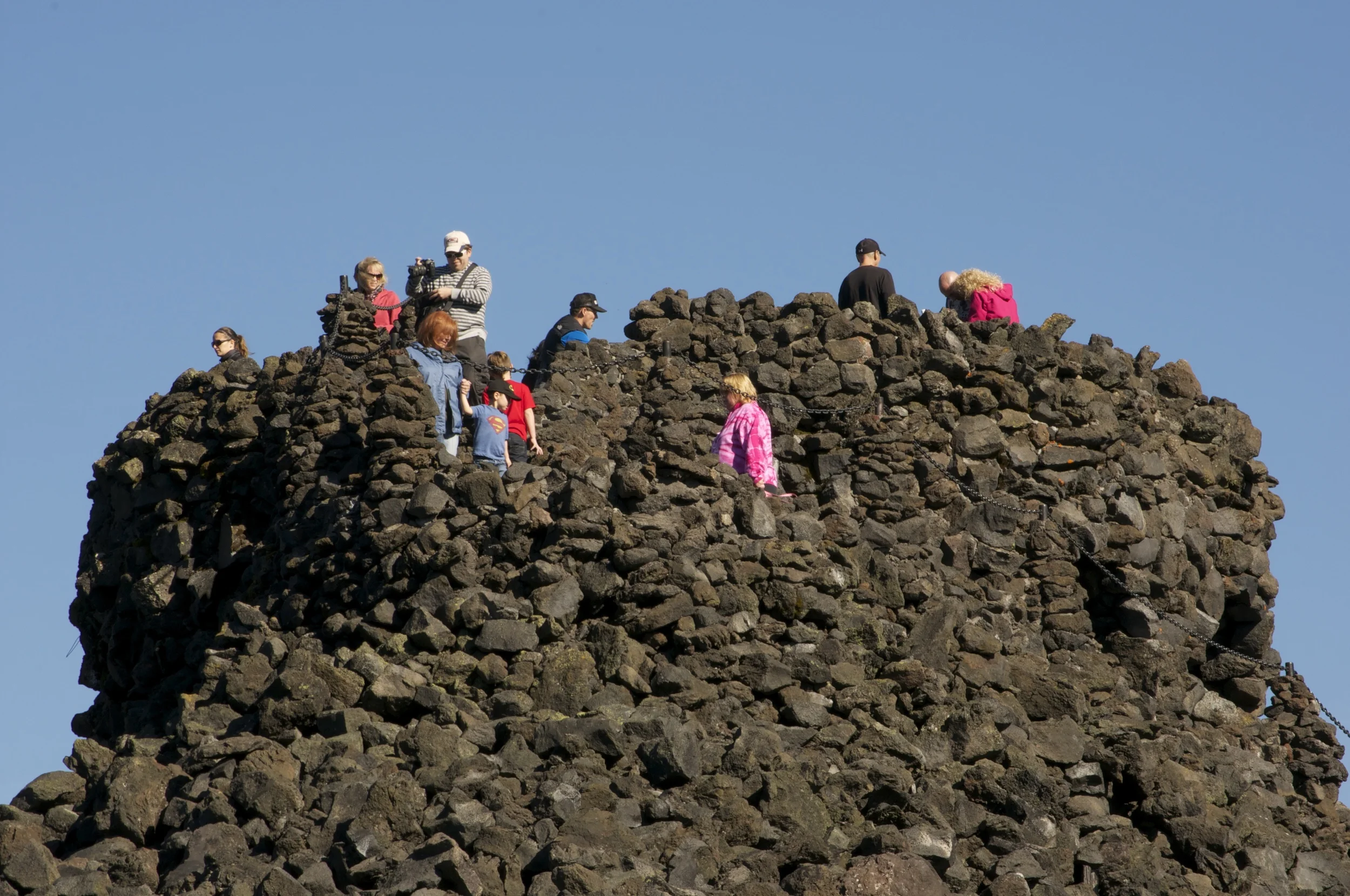 Visitors contribute a splash of color as they climb to the top of the Dee Wright Observatory, built in 1935 by the CCC.