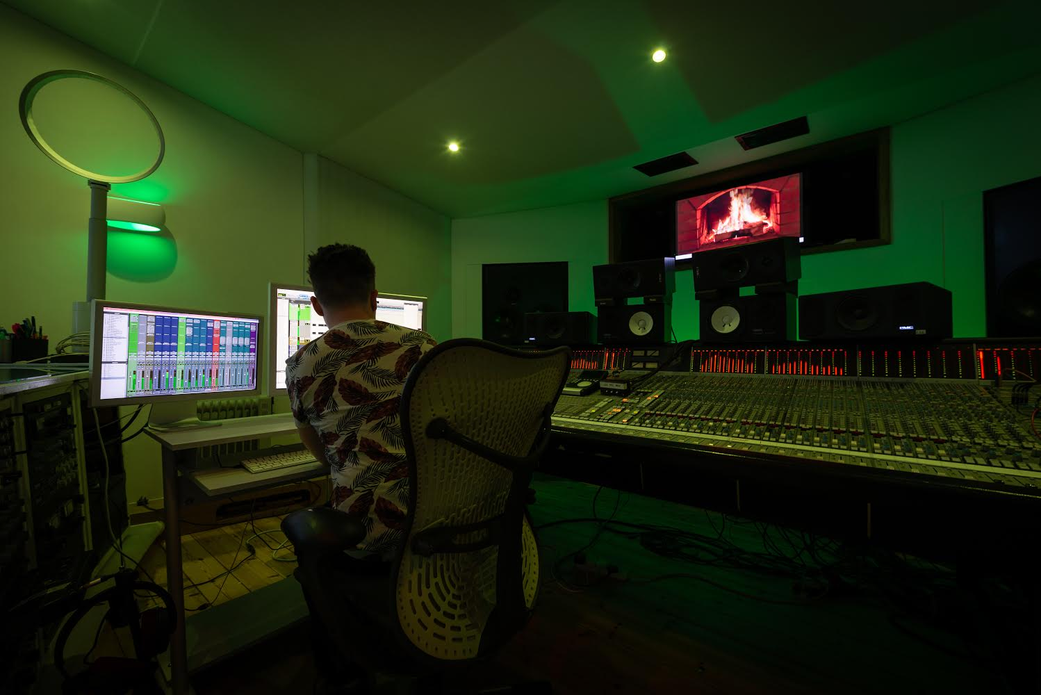 Shane Shanahan is working at Westpoint Studios with multiple monitors, audio equipment, and a large SSL mixing console, illuminated by green lighting.